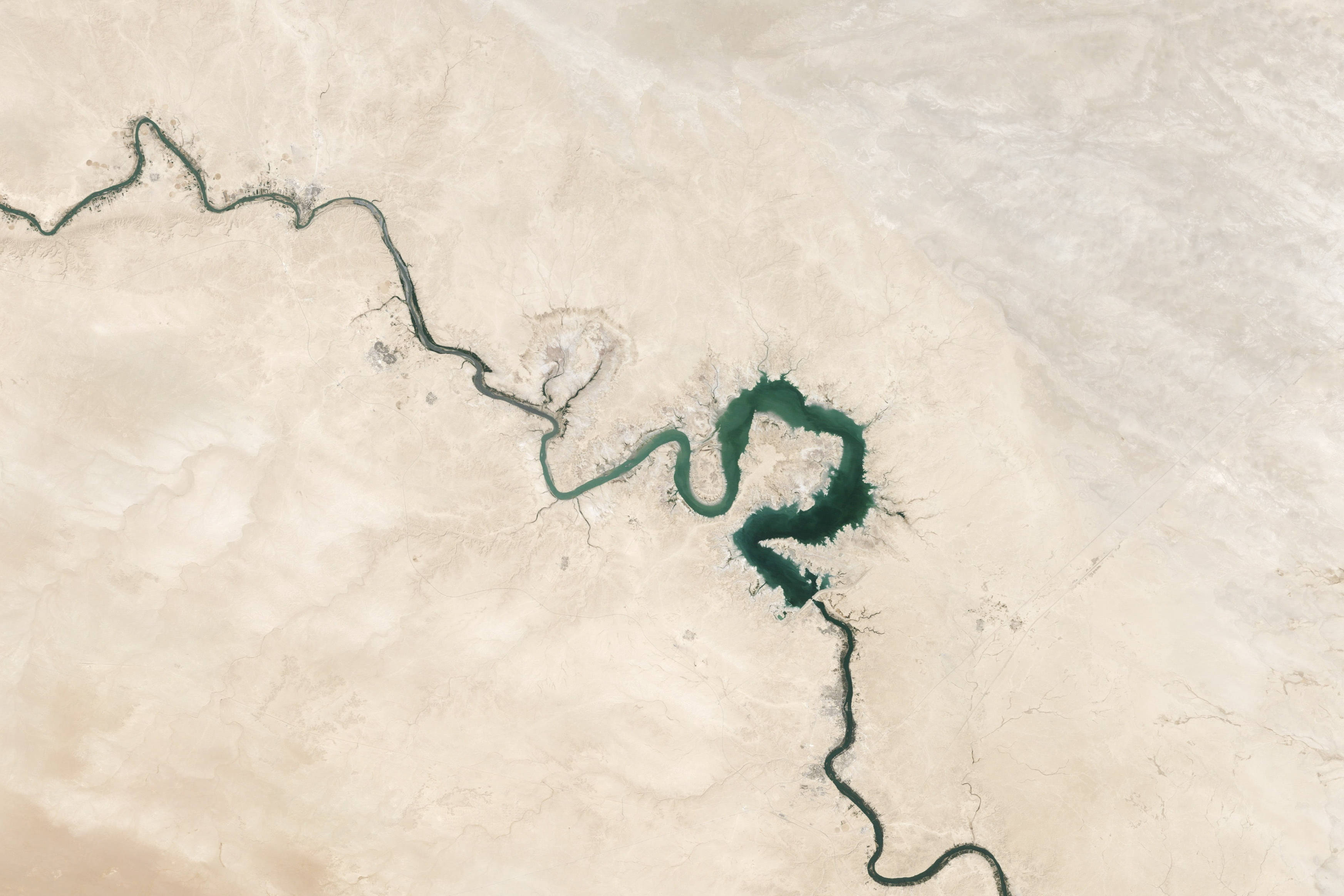 Iraq 桌布 壁紙 — 一條蜿蜒的河流穿過廣闊的米色沙漠，在乾旱的景觀中形成一個心形綠洲。