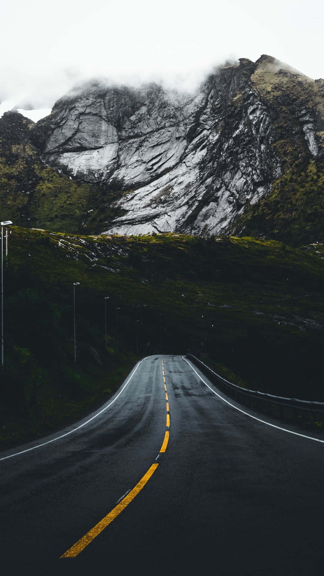 highway 桌布 壁紙 — 一條蜿蜒的瀝青公路在陰天下彎向高聳的霧山。