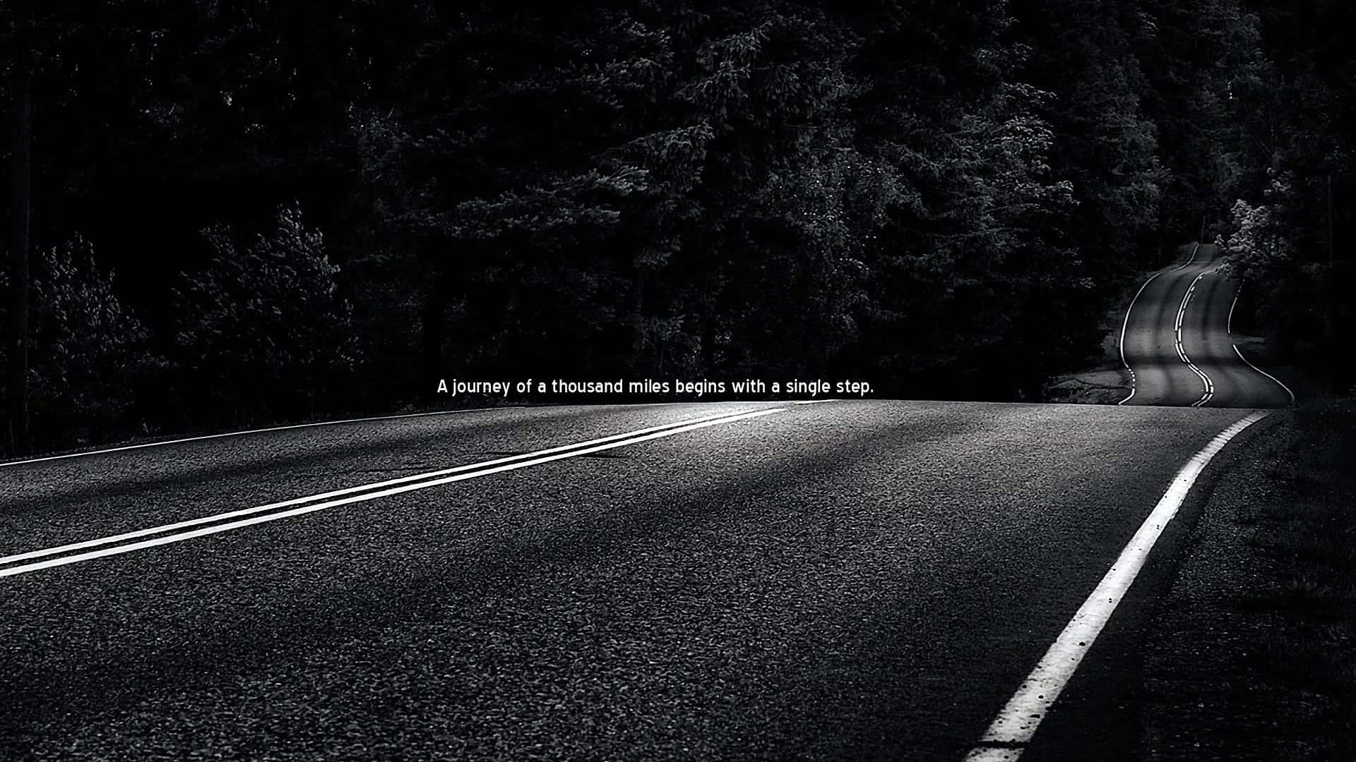 Motivational Quotes Black 桌布 壁紙 — 一條蜿蜒的瀝青路在陰鬱的黑白燈光下彎入黑暗的森林，並帶有鼓舞人心的文字疊加。