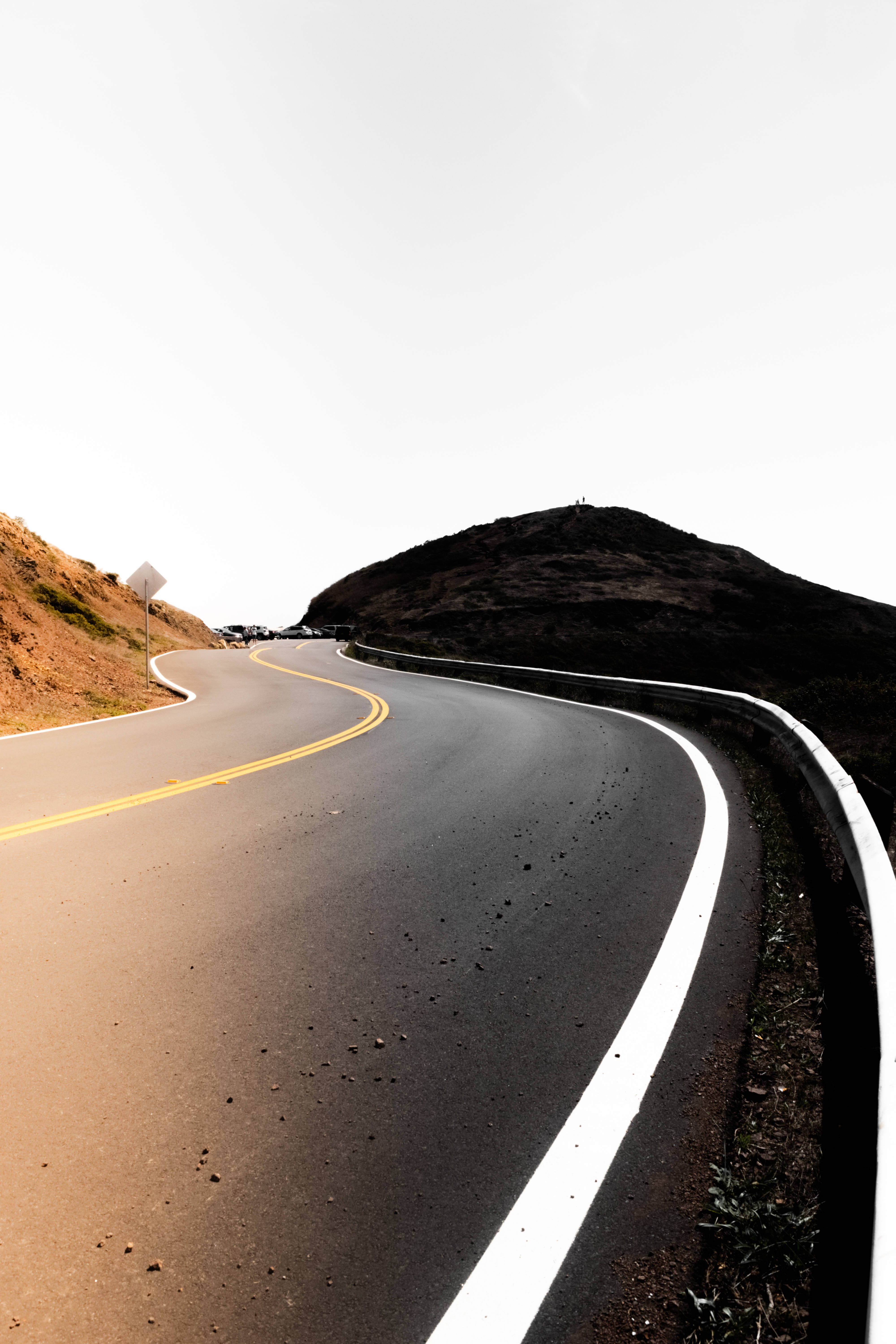 Road 桌布 壁紙 — 一條蜿蜒的瀝青路穿過一片荒涼的風景，有黑暗的山丘和蒼白的天空。