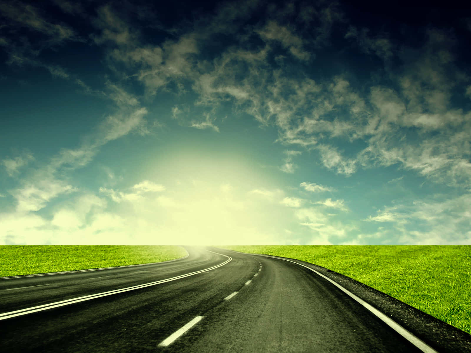 highway 桌布 壁紙 — 一條蜿蜒的瀝青道路在戲劇性的多雲天空和明亮的陽光下穿過充滿活力的綠色田野。