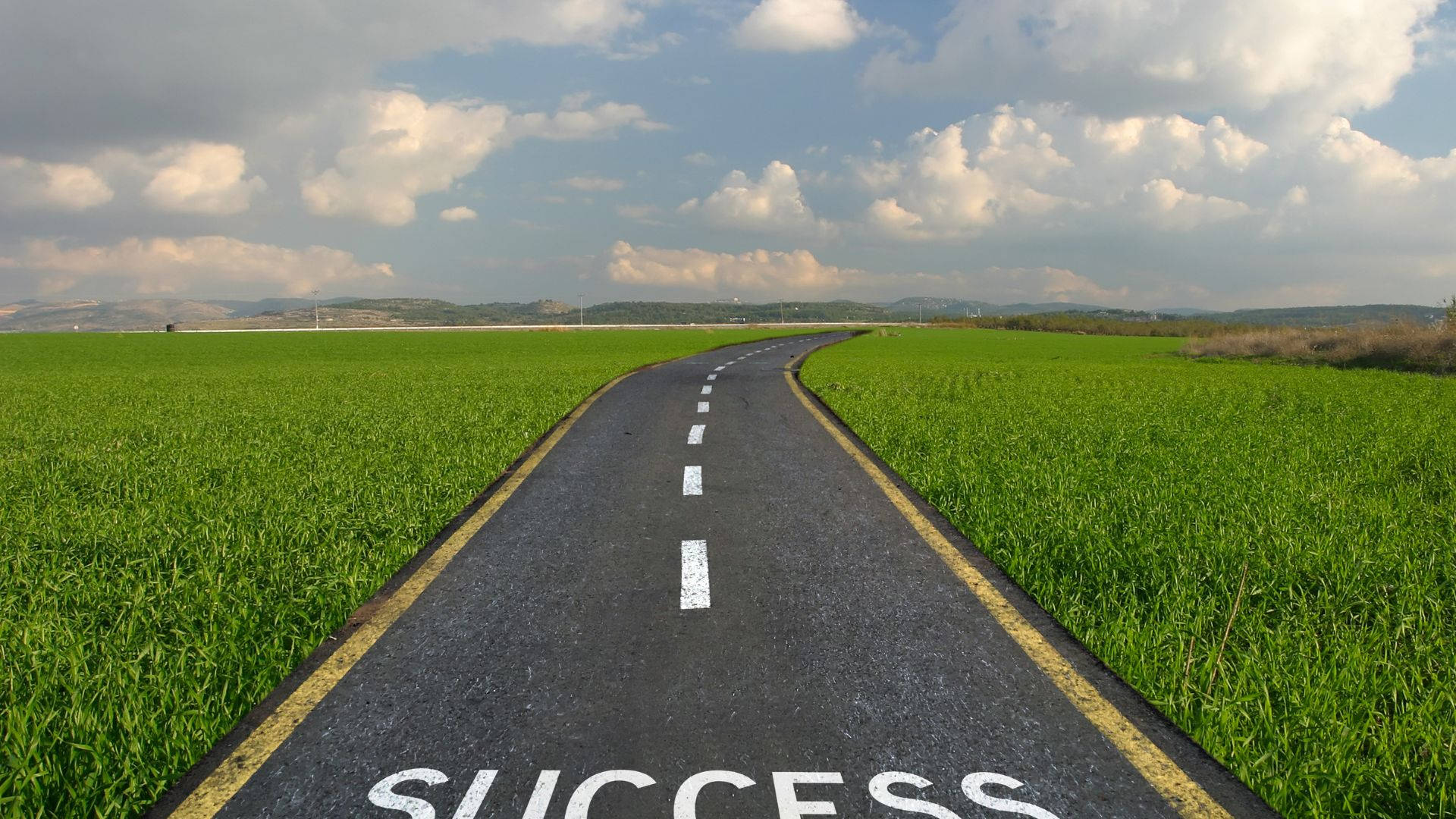 Success 桌布 壁紙 — 一條蜿蜒的瀝青道路標有「成功」，在部分多雲的天空下穿過充滿活力的綠色田野。