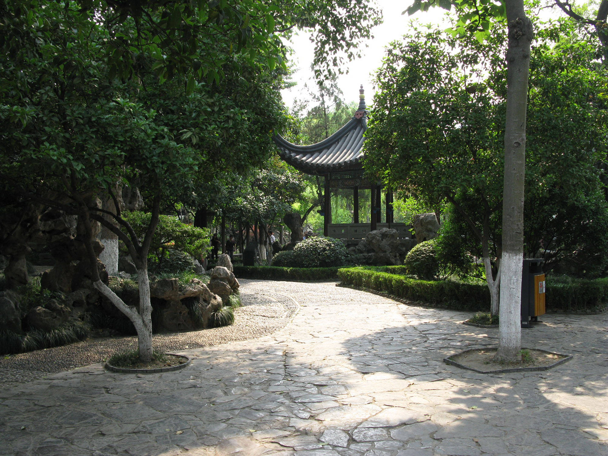 Nanjing 桌布 壁紙 — 一條蜿蜒的石徑穿過茂密的綠色花園，通往隱藏在樹木和岩石間的傳統中式亭子。
