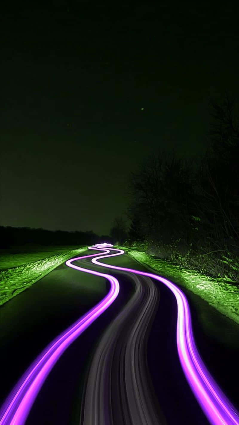 Neon Green And Purple 桌布 壁紙 — 一條蜿蜒的道路在夜晚被移動車輛的鮮豔紫色光軌和發光的綠色路邊點綴照亮。