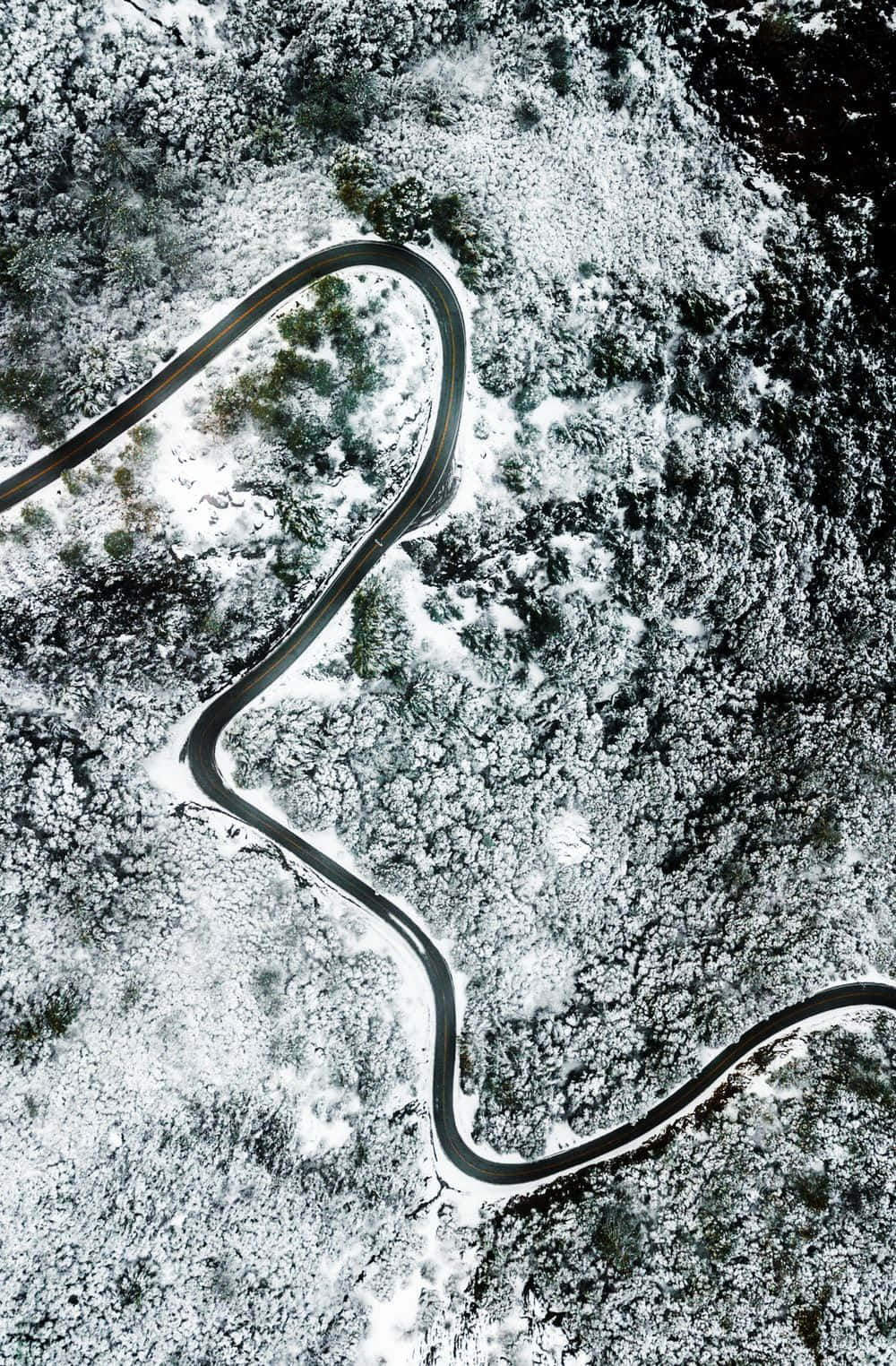 Road 桌布 壁紙 — 一條蜿蜒的道路從空中俯瞰穿過白雪覆蓋的森林。