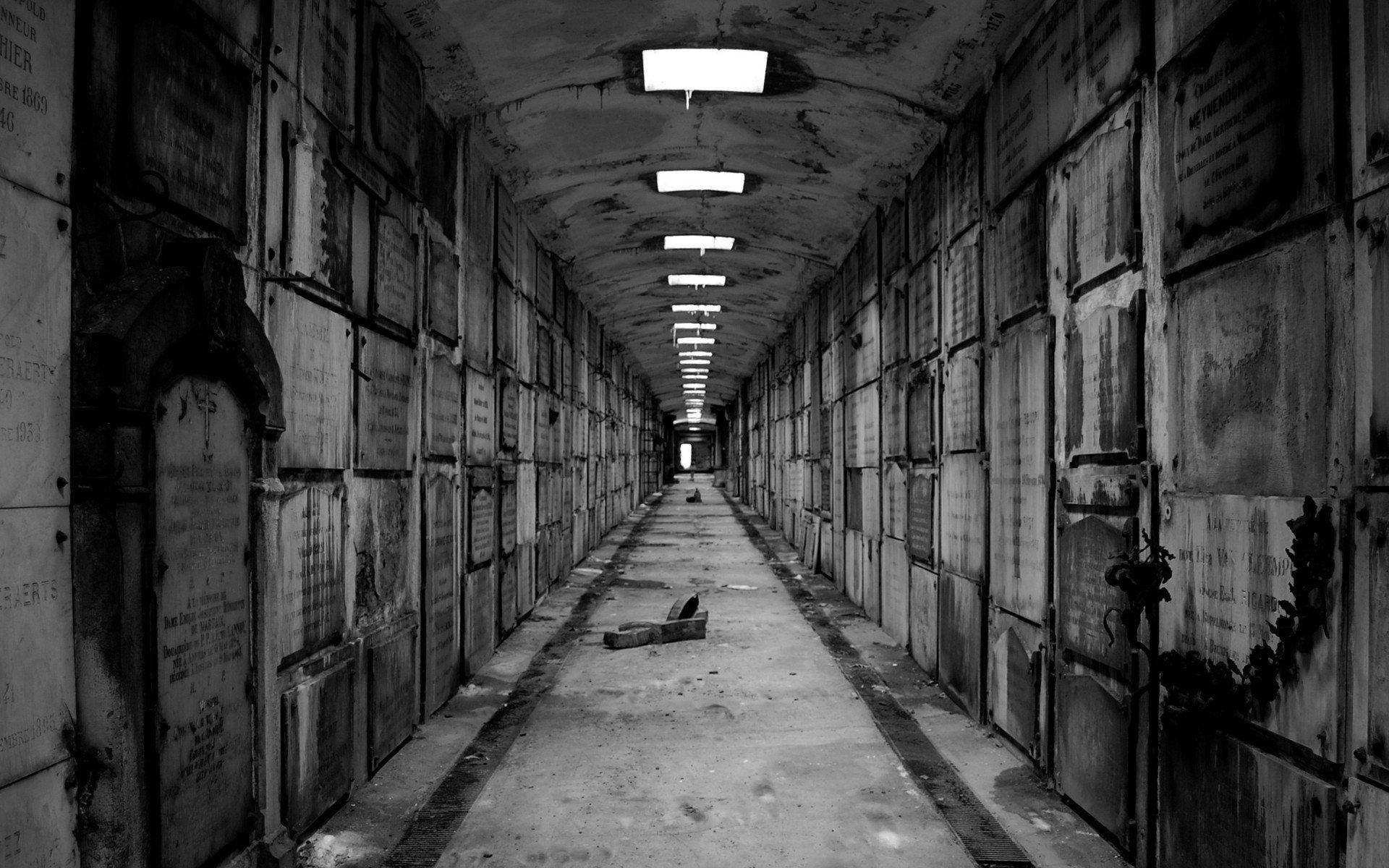 詭異的GIF 桌布 壁紙 — 一條被遺忘的墓園中燈光昏暗的長廊，兩旁排列著風化的墓碑和閃爍的吊燈。