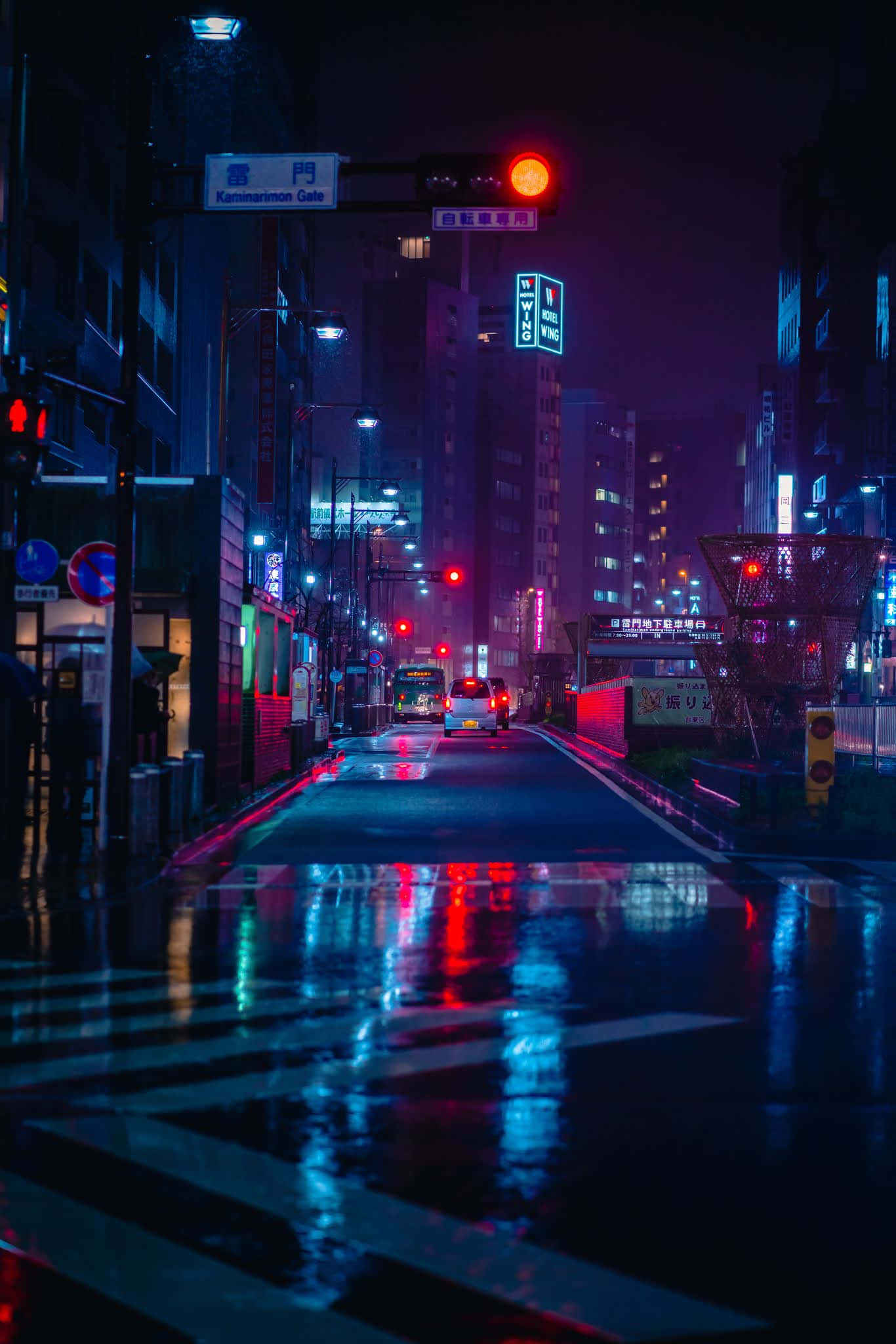 夜景城市 桌布 壁紙 — 一條被雨水浸濕、霓虹燈閃爍的東京街道在夜晚反射出交通號誌和招牌上鮮豔的紅藍燈光。