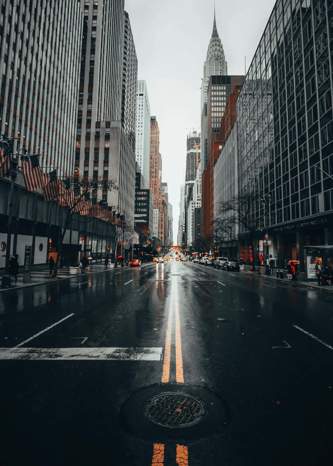 City Street 桌布 壁紙 — 一條被雨水浸濕的城市街道，在陰天之下延伸向一座高聳的摩天大樓。