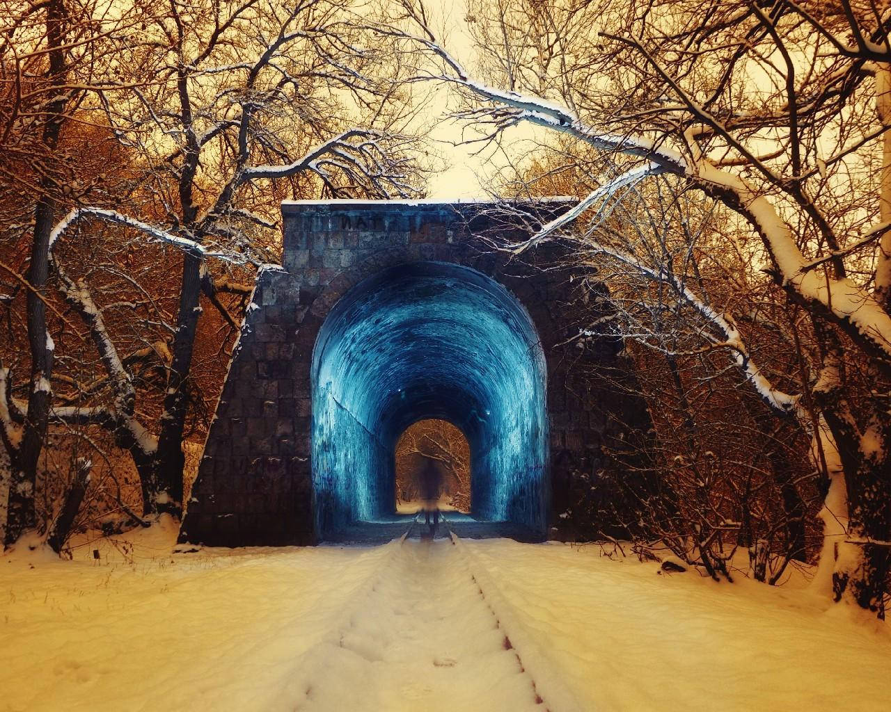 Armenia 桌布 壁紙 — 一條被雪覆蓋的小路通向一個發光的藍色石頭隧道，在溫暖的金色天空下，由光禿禿的冬季樹木環繞。