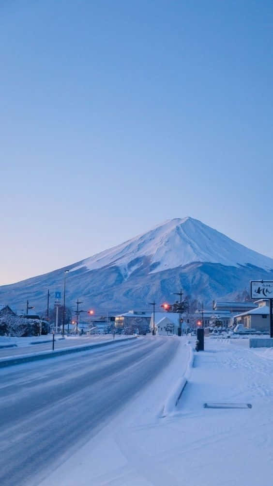 日本 桌布 壁紙 — 一條被雪覆蓋的道路在黎明時分晴朗的藍天下通往雄偉的富士山。
