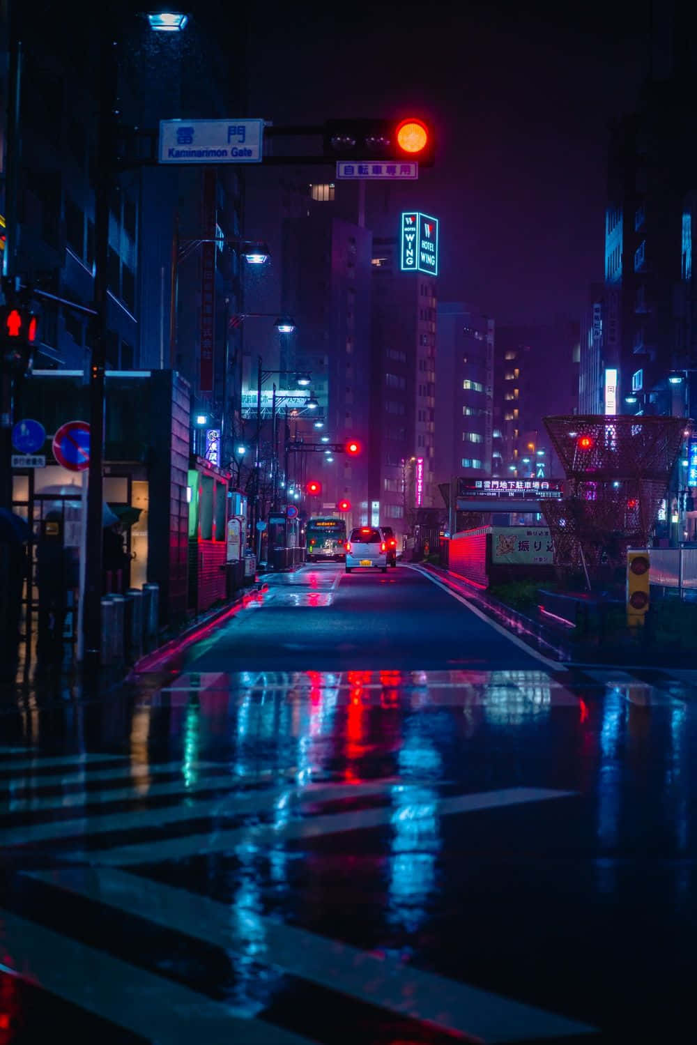 桌布 壁紙 — 一條被霓虹燈浸透的東京街道在夜晚，在發光的交通號誌下，將鮮豔的紅色和藍色燈光反射在潮濕的路面上。