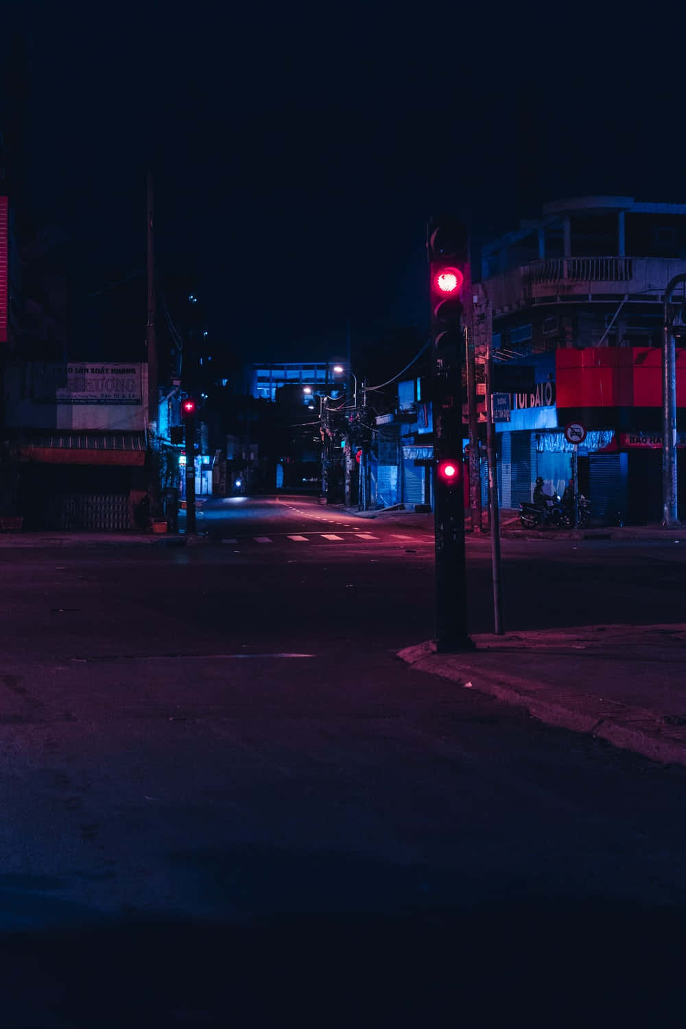 Dark Crossroad 桌布 壁紙 — 一條被霓虹燈浸透的都市街道，夜晚中紅色交通燈在潮濕的路面上投射出超現實的光芒。
