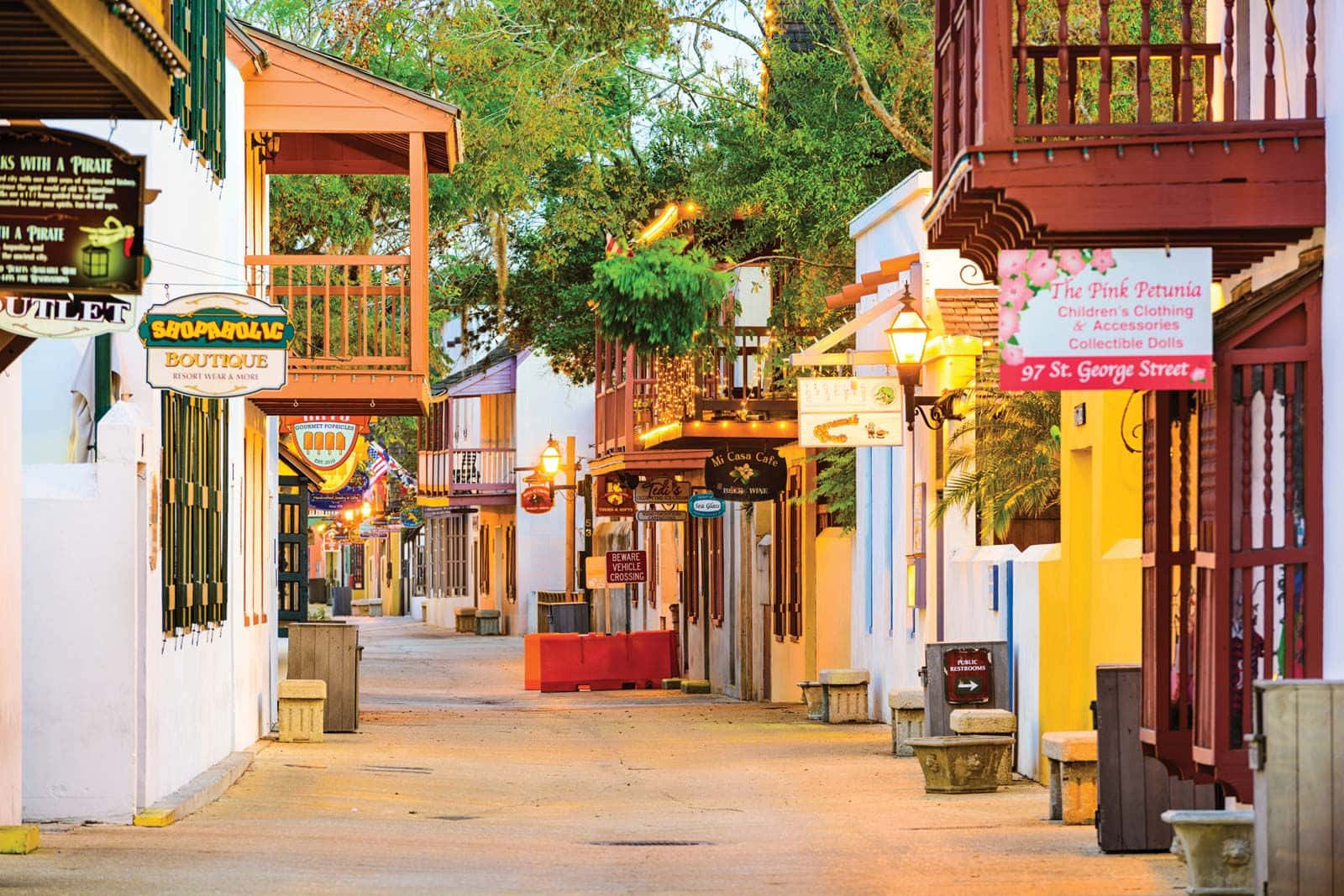 Saint Augustine Florida 桌布 壁紙 — 一條迷人的街道，兩旁是色彩繽紛的木製陽台和精品店，沐浴在溫暖的金色夕陽中。