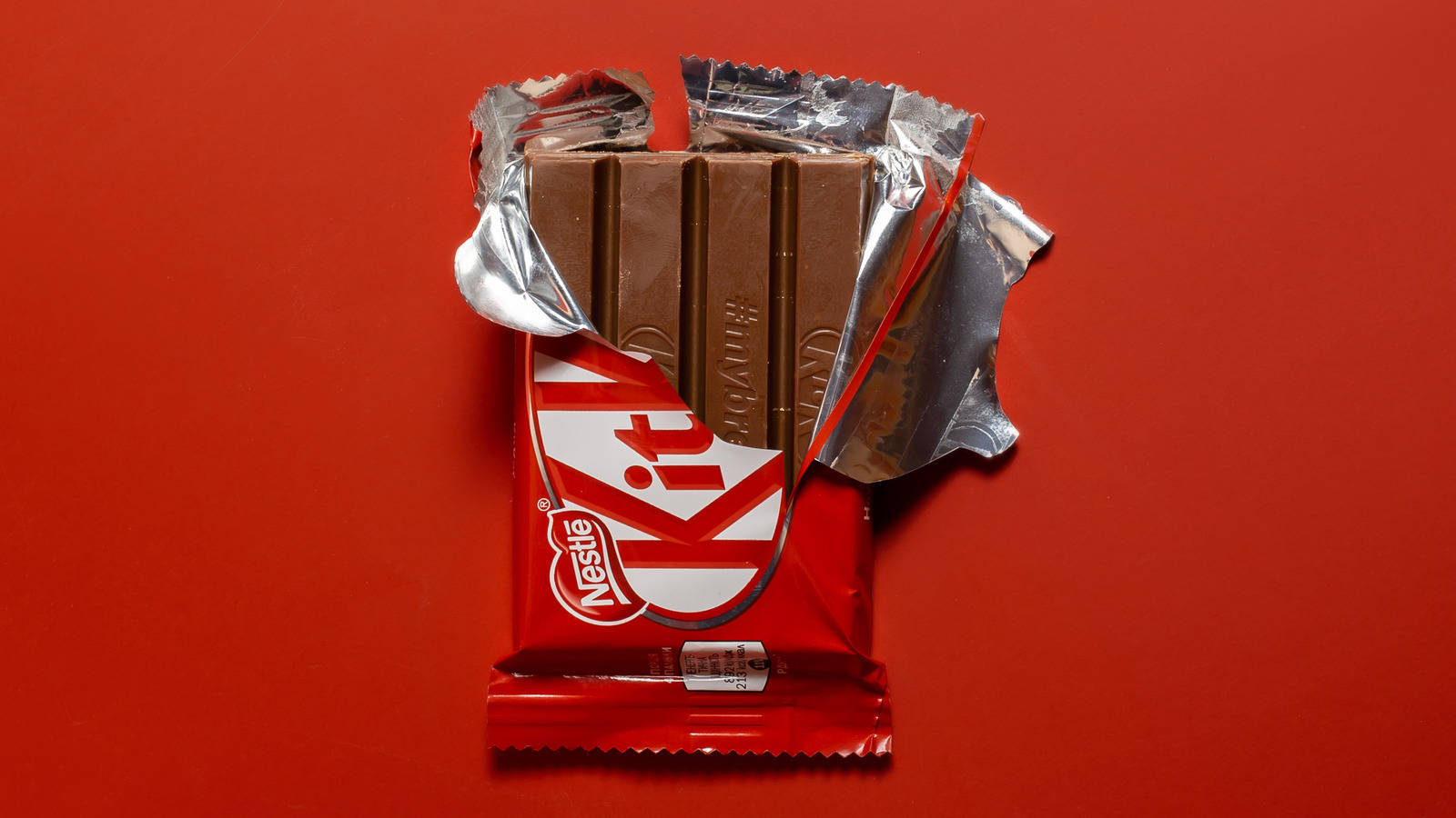 紅色動圖 桌布 壁紙 — 一條部分打開的 KitKat 巧克力棒，帶有銀色錫箔紙，襯托在鮮紅色背景上。