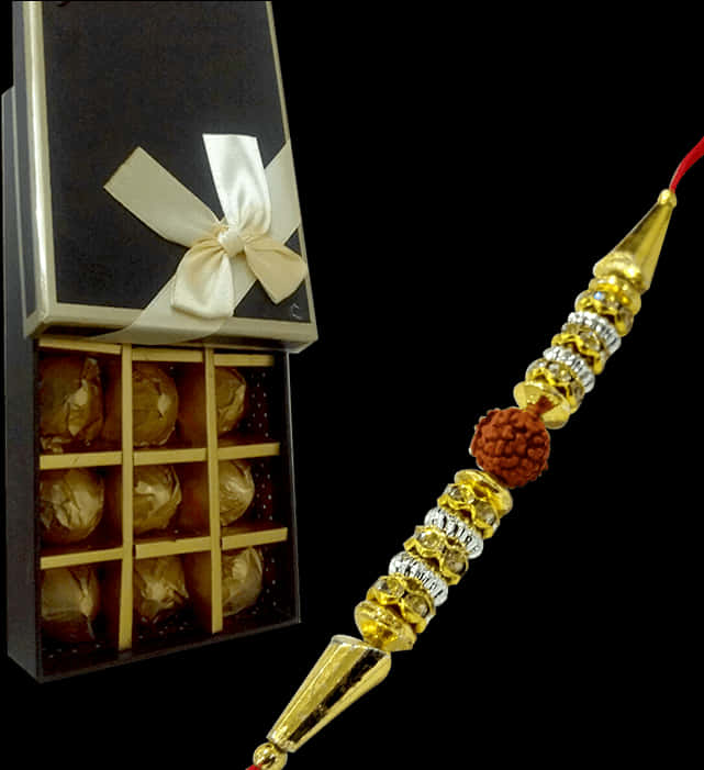 Bracelet 桌布 壁紙 — 一條金色珠子的Rakhi與一顆Rudraksha種子放在一個打開的巧克力禮物盒旁邊，盒子上繫著奶油色蝴蝶結。