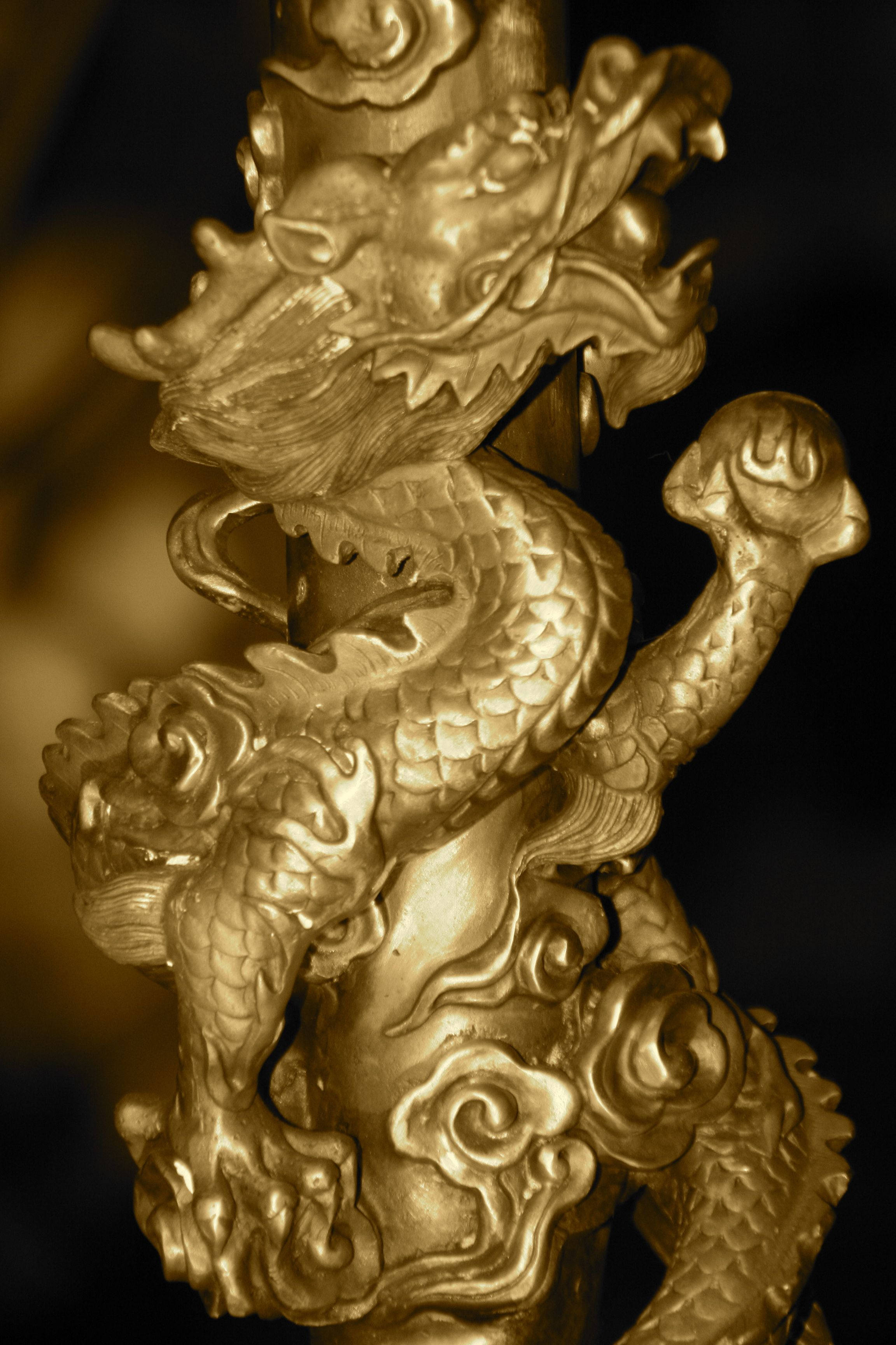 Gold Dragon 桌布 壁紙 — 一條金色龍雕塑動態地纏繞在柱子上，帶有精細的鱗片和飄逸的鬃毛，背景為深色。