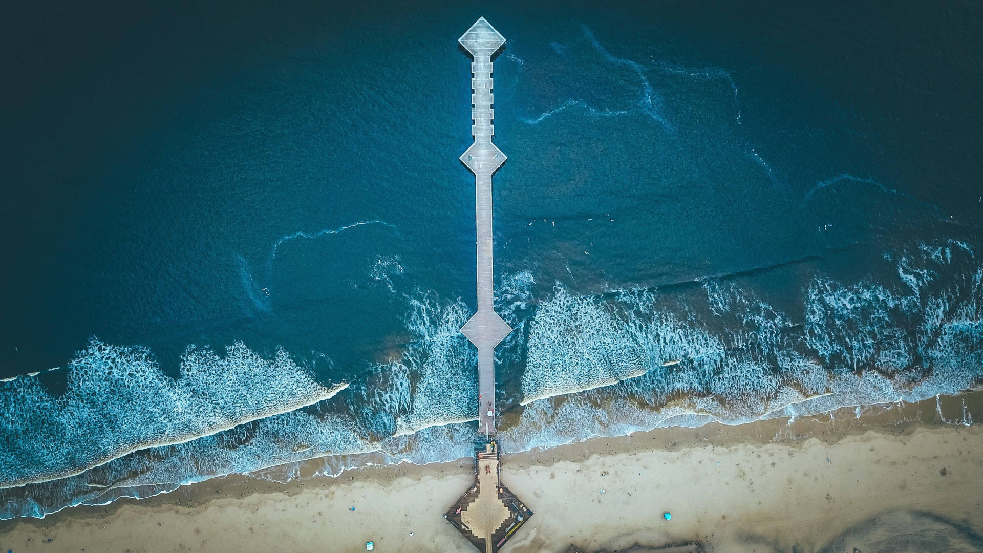 碼頭延伸至海洋，海浪拍打岸邊的航拍視圖。