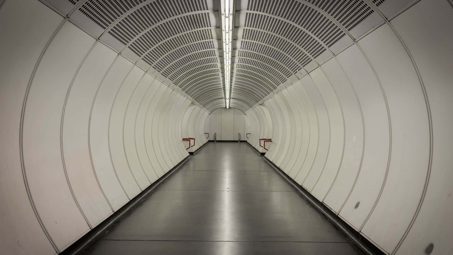 Subway 桌布 壁紙 — 一條長而彎曲的白色地鐵隧道，帶有反光地板和頭頂燈光，向遠方延伸。