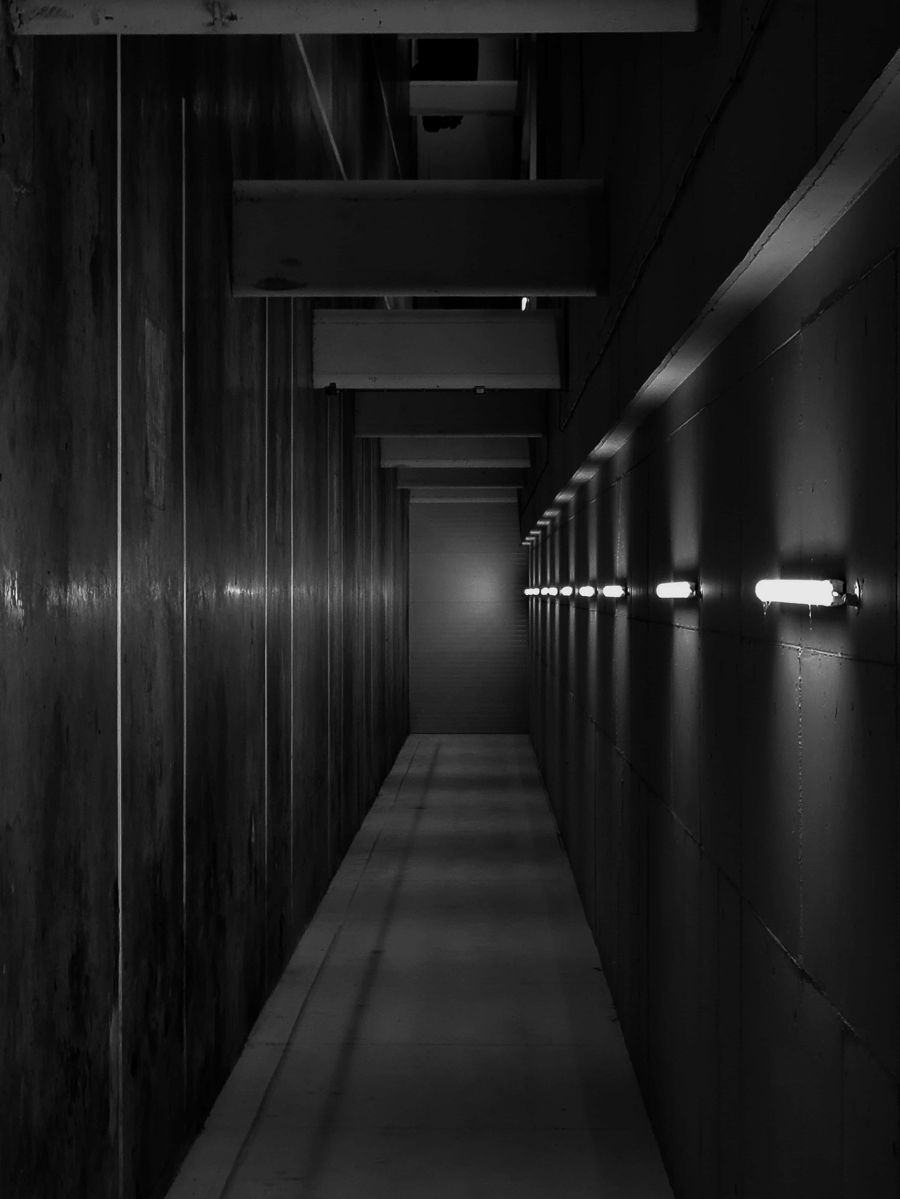 hallway 桌布 壁紙 — 一條長而窄的走廊，帶有紋理牆壁和螢光燈，逐漸消失在明亮的消失點。