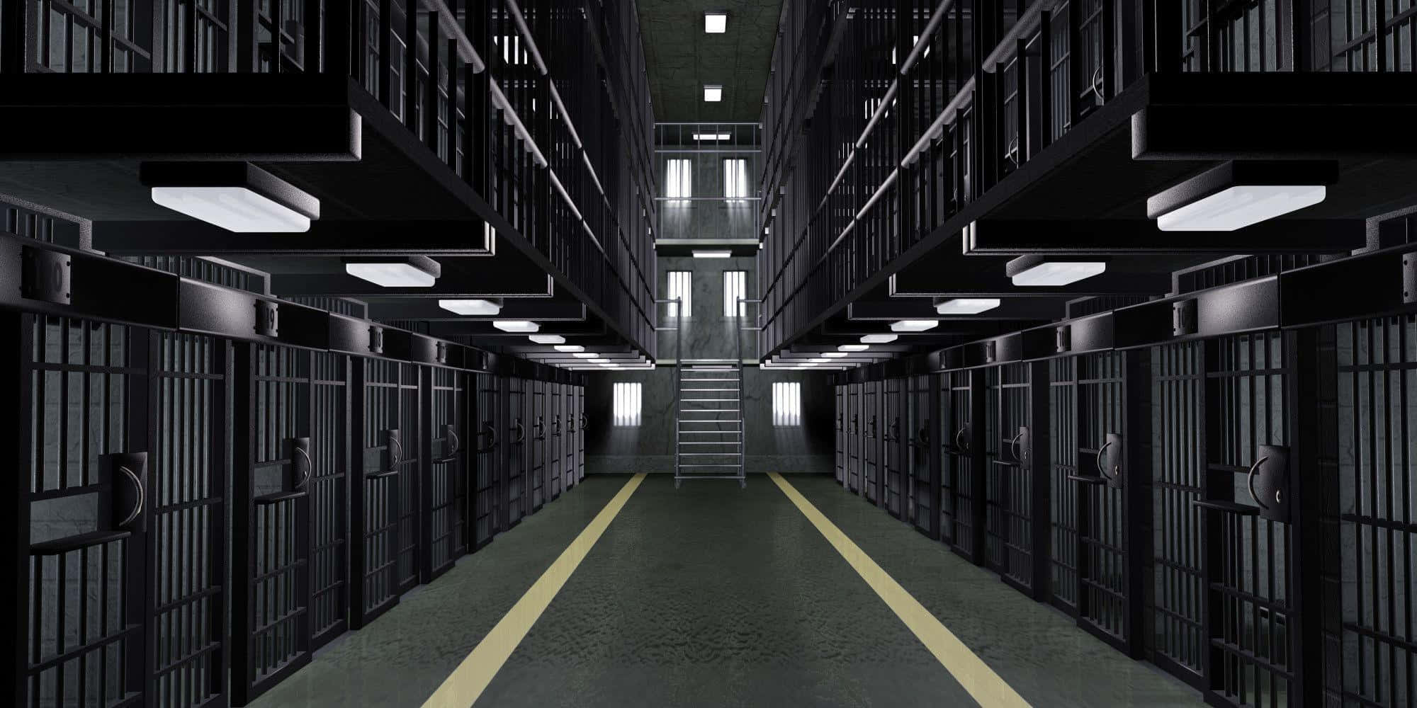Jail 桌布 壁紙 — 一條長長的、燈光昏暗的監獄走廊，兩側排列著帶有鐵欄的牢房，中央有樓梯向上延伸。