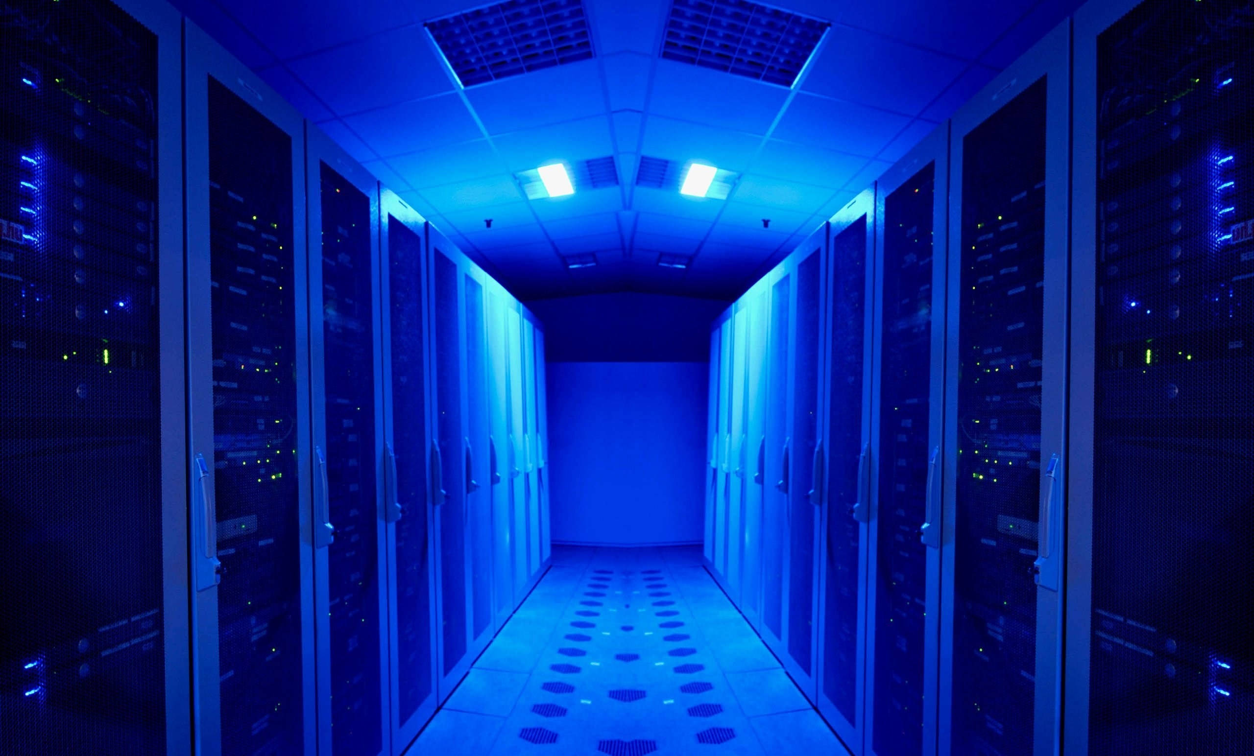 room 桌布 壁紙 — 一條長長的伺服器機架走廊，沐浴在冷藍色燈光中，發光的指示燈營造出未來科技氛圍。