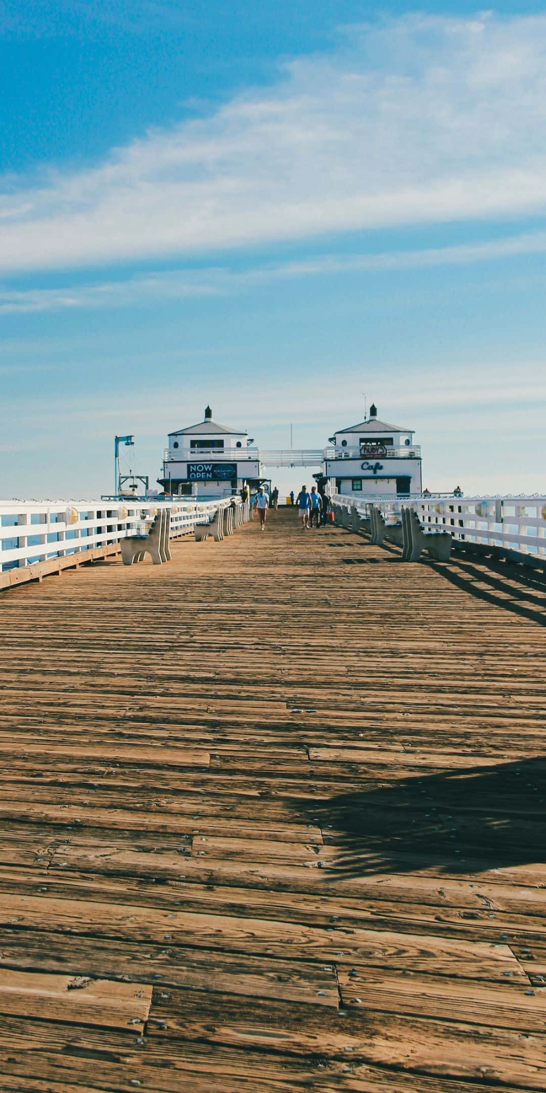California Aesthetic 桌布 壁紙 — 一條長長的木碼頭伸向兩座白色建築，天空湛藍，雲朵輕柔。