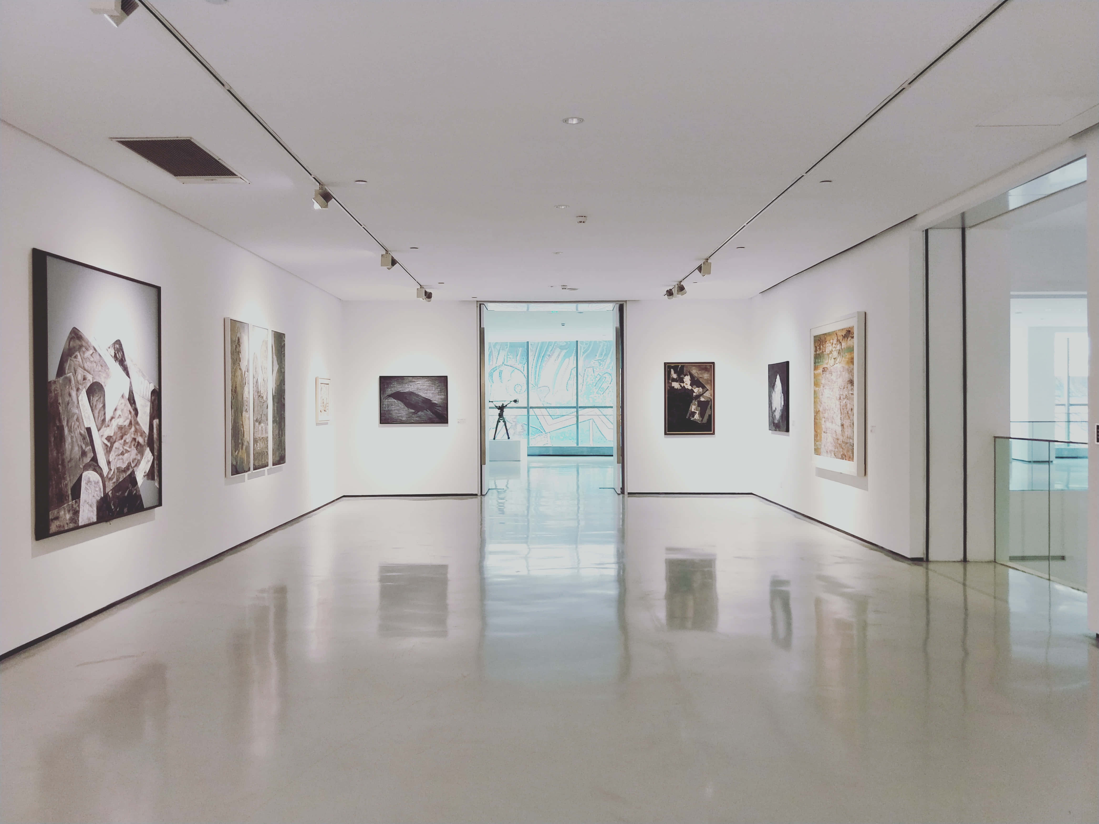 Gallery 桌布 壁紙 — 一條長長的極簡主義藝術畫廊走廊，拋光地板反射著軌道燈光下的裱框藝術品。