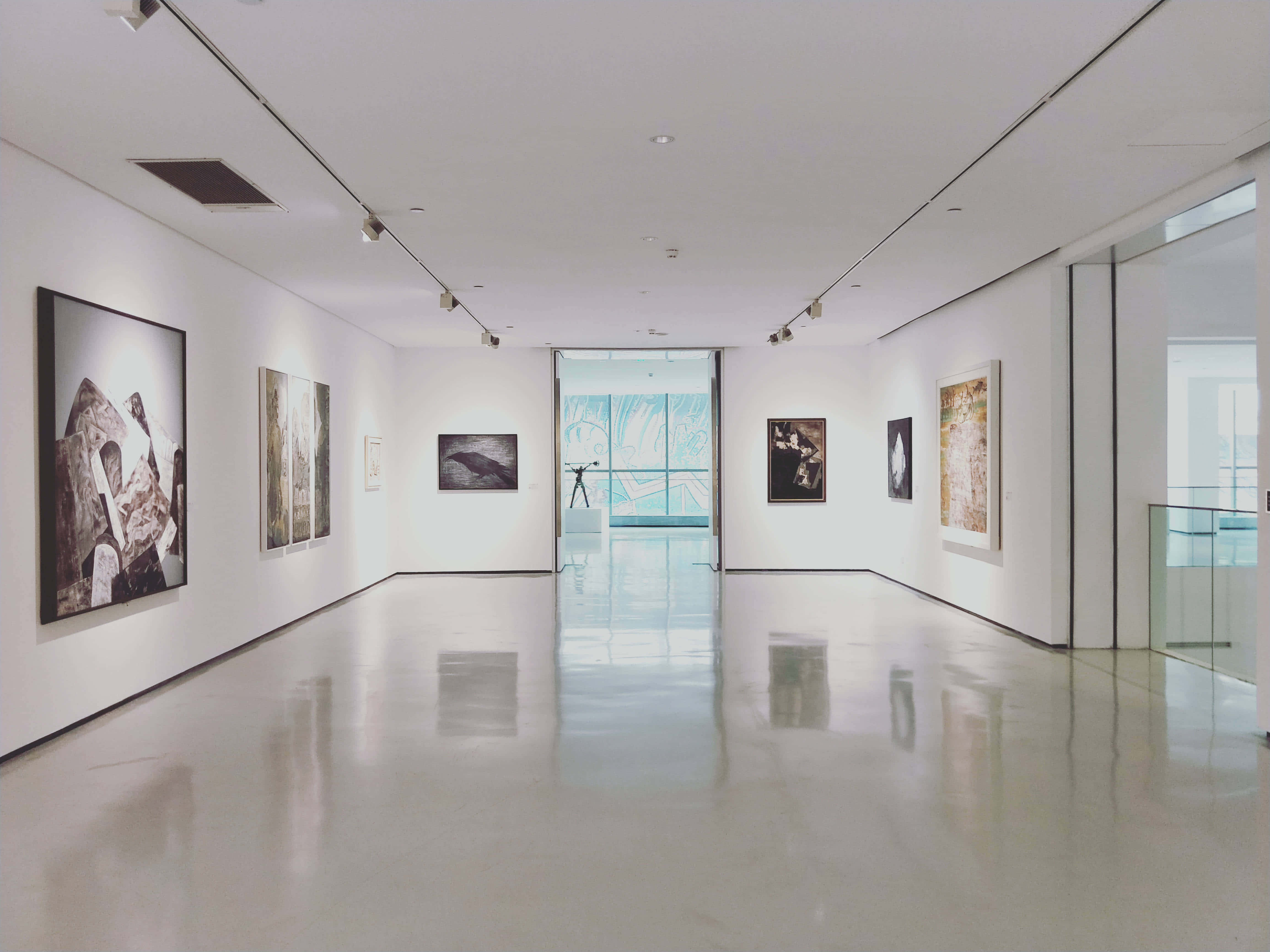 Gallery 桌布 壁紙 — 一條長長的極簡主義藝術畫廊走廊，拋光地板反射著軌道燈光下裝裱的抽象和具象藝術品。