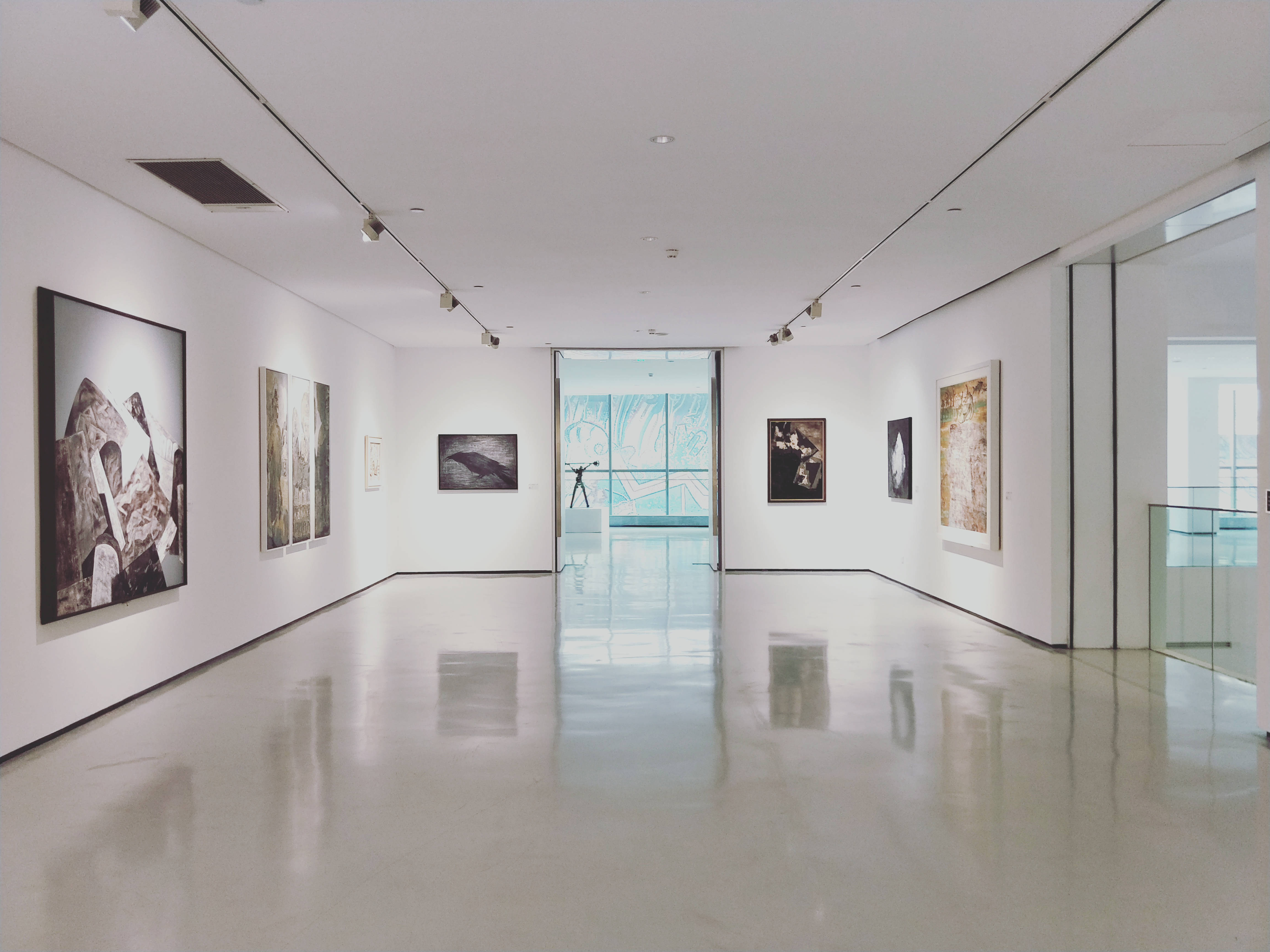 Gallery 桌布 壁紙 — 一條長長的極簡主義藝術畫廊走廊，拋光地板反射著軌道燈光下的抽象和具象框裝藝術品。