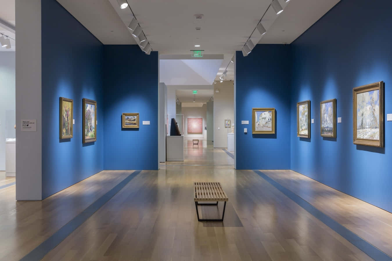 Museum 桌布 壁紙 — 一條長長的畫廊走廊，深藍色牆壁上掛滿了裱框畫作，拋光地板中央放著一張木長凳。