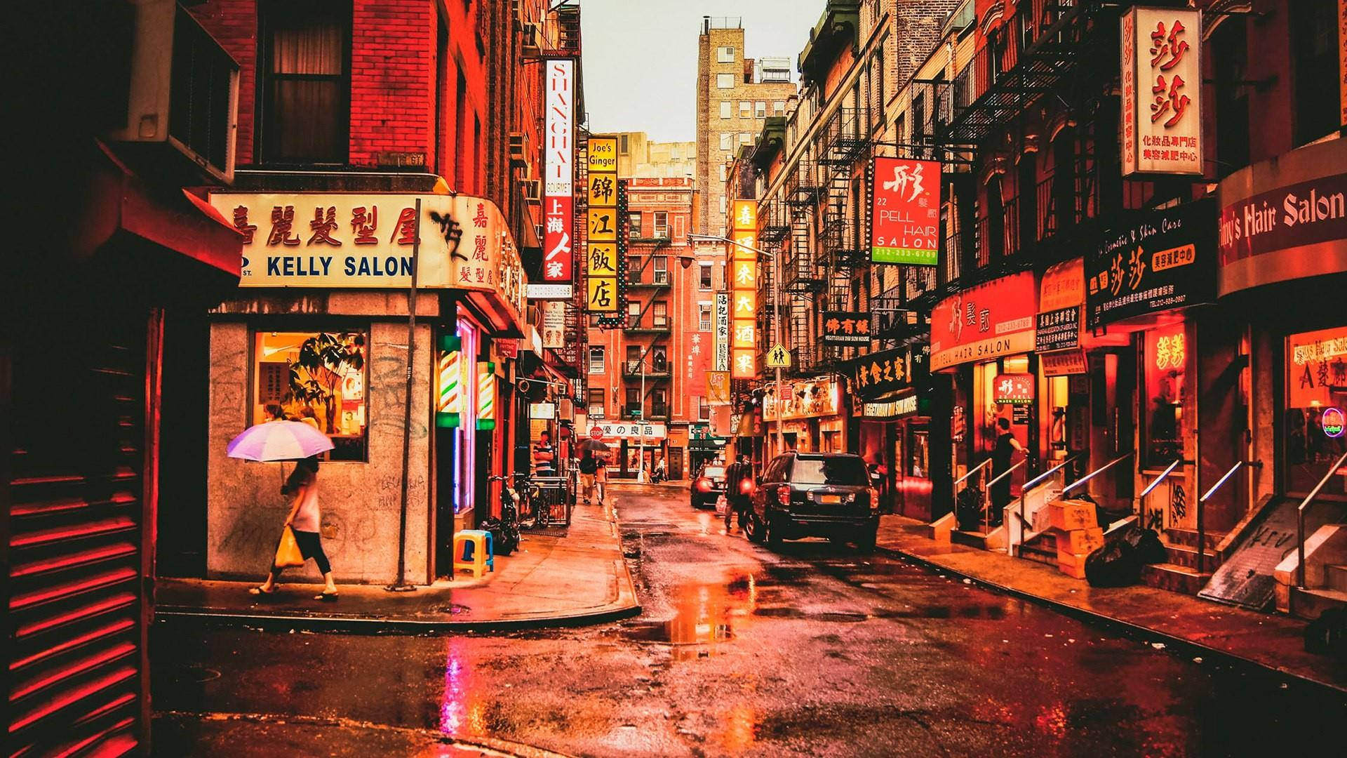 唐人街 桌布 壁紙 — 一條雨中的城市小巷，被中文招牌的溫暖霓虹燈光沐浴，倒映在濕漉漉的路面上。