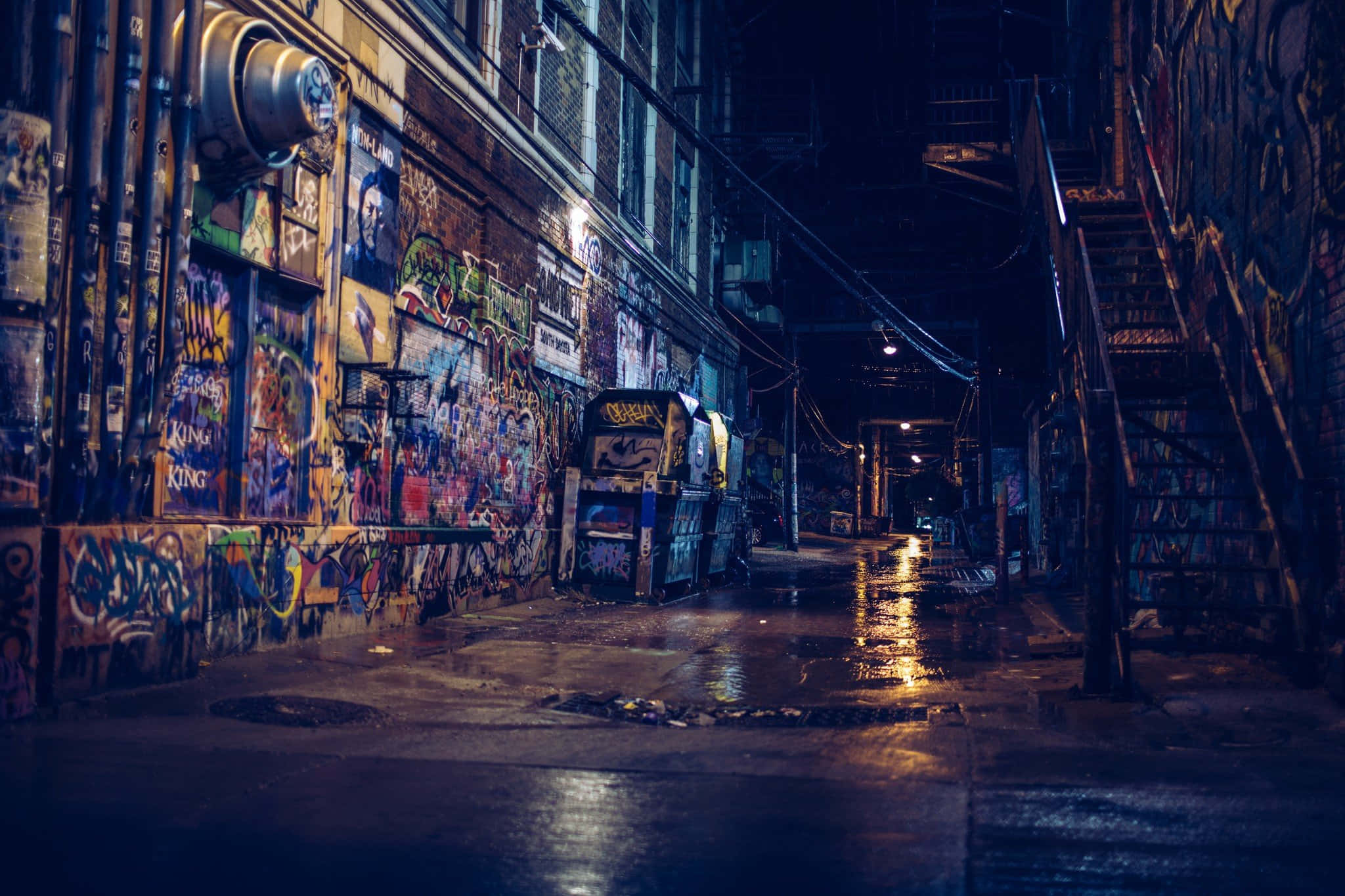 Alleyway 桌布 壁紙 — 一條雨濕的城市後巷在夜晚閃爍著霓虹反射和充滿活力的塗鴉牆壁。
