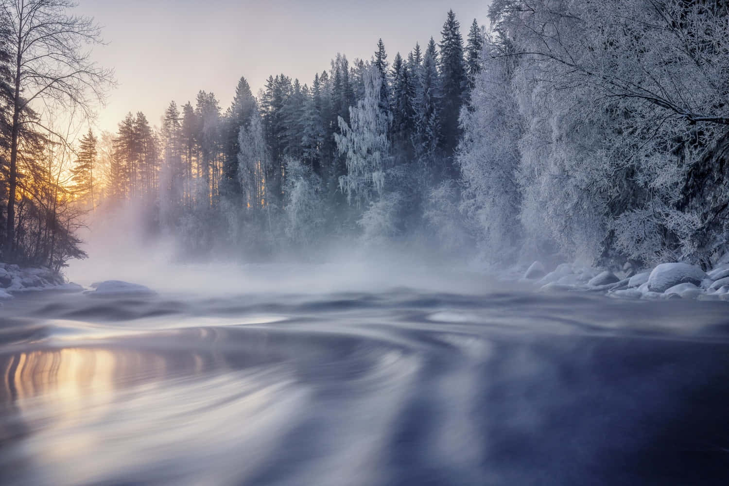 寒冷 桌布 壁紙 — 一條霧氣瀰漫的冬日河流流過積雪覆蓋的樹木，金色的日出光線穿過森林。