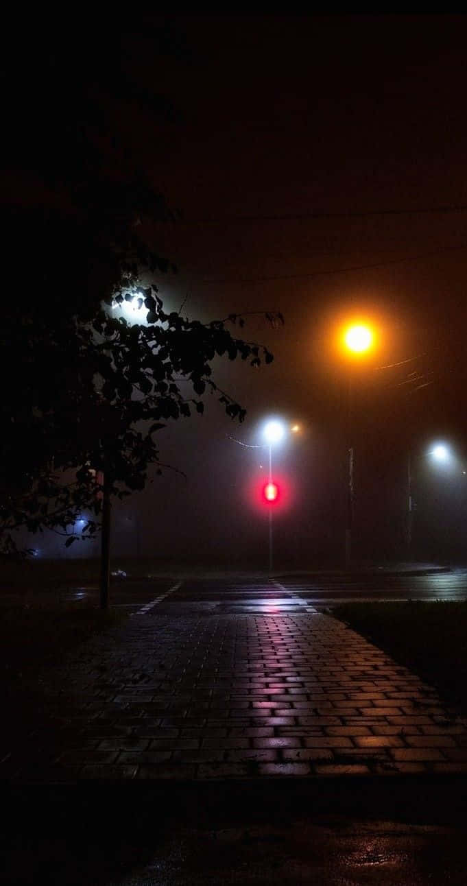 Light 桌布 壁紙 — 一條霧氣瀰漫的夜晚街道，被發光的街燈和紅色交通號誌燈照亮，在濕漉漉的鵝卵石上投下倒影。