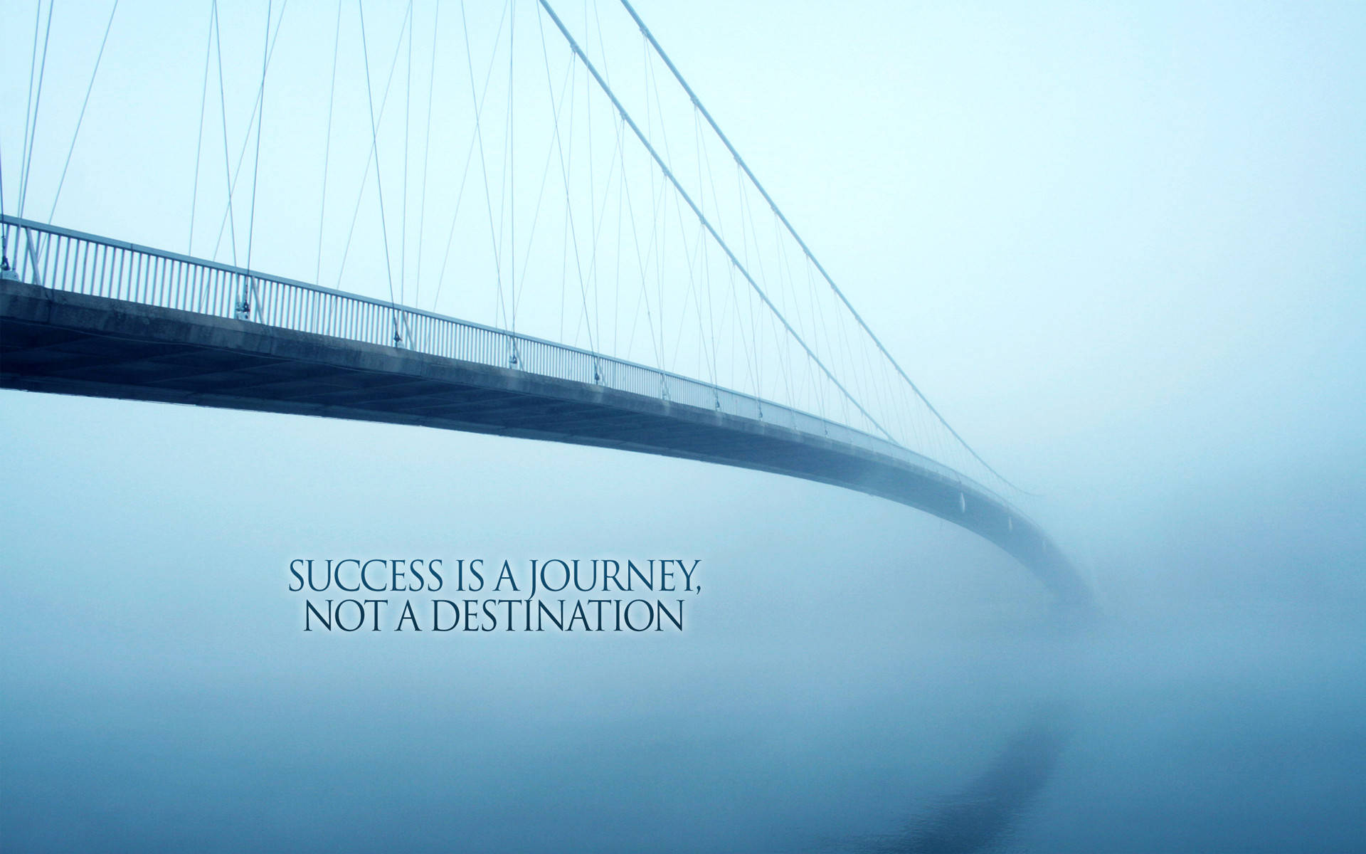 Success 桌布 壁紙 — 一條霧濛濛的吊橋彎曲入霧中，上面疊加了名言「成功是一段旅程，而不是目的地」。