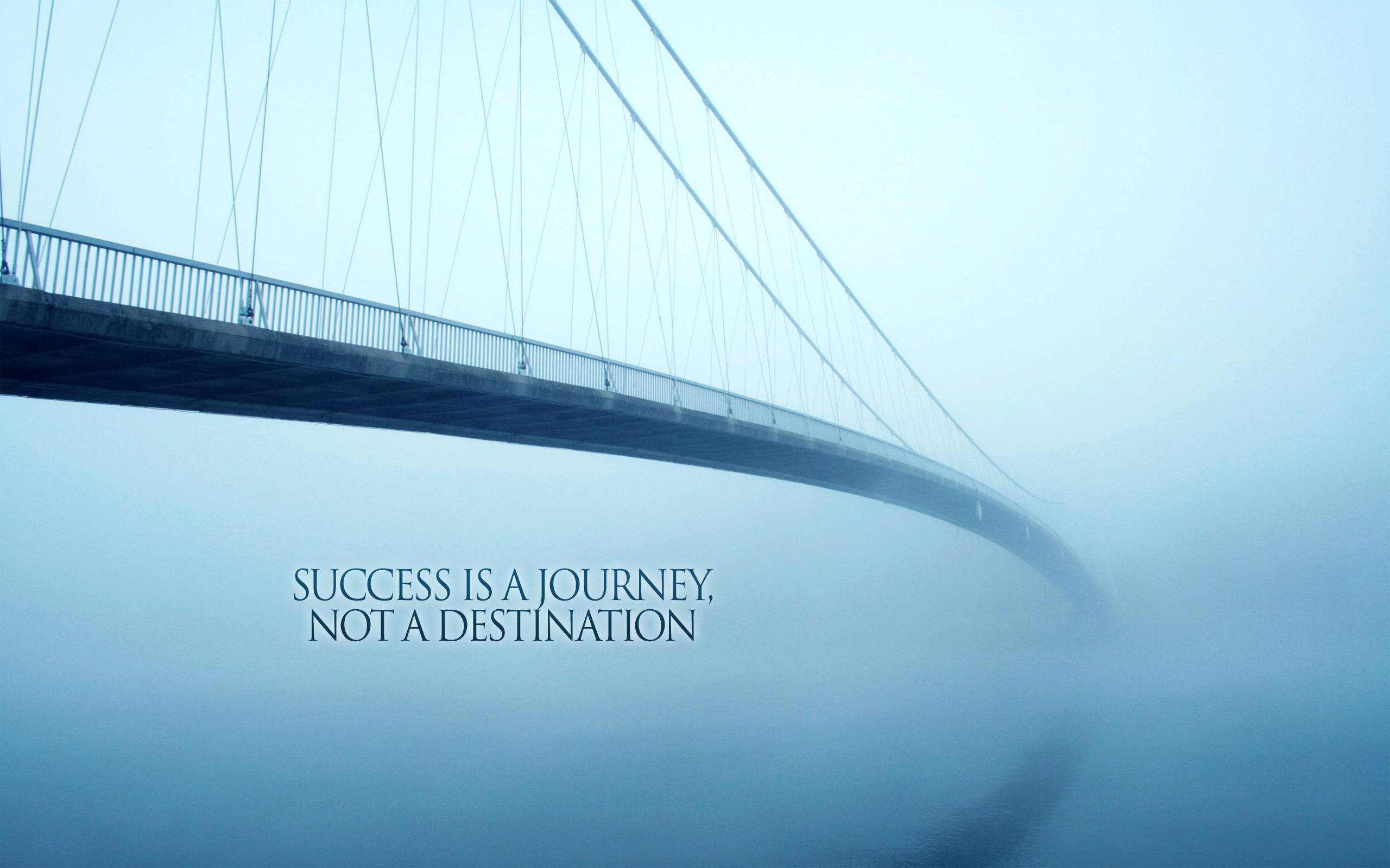 Success 桌布 壁紙 — 一條霧濛濛的吊橋彎曲進入霧中，上面疊加了名言「成功是一段旅程，而不是目的地」。