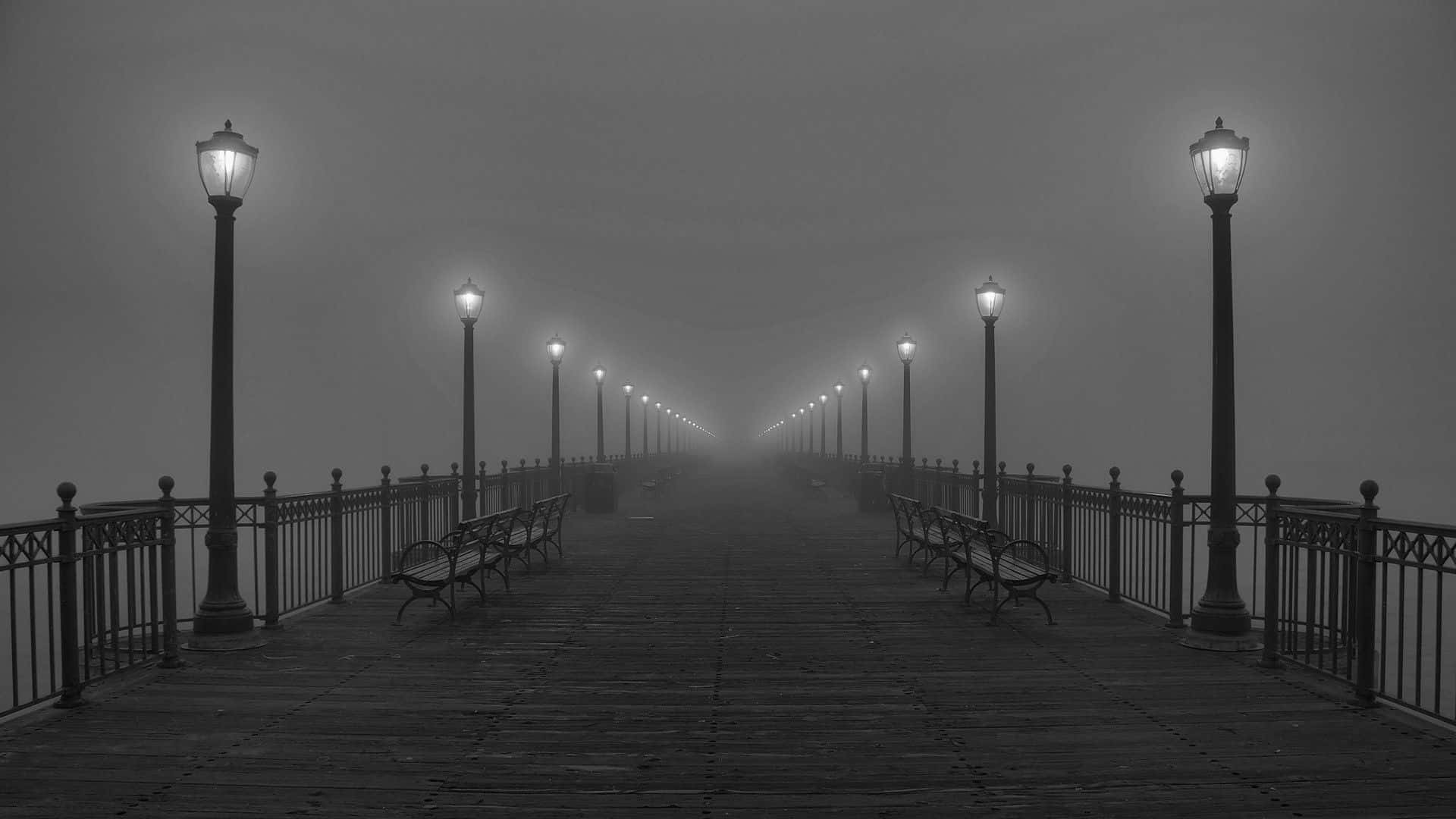 Black And White Street 桌布 壁紙 — 一條霧濛濛的黑白碼頭延伸進霧中，木棧道兩旁掛著發光的燈籠和空長椅。