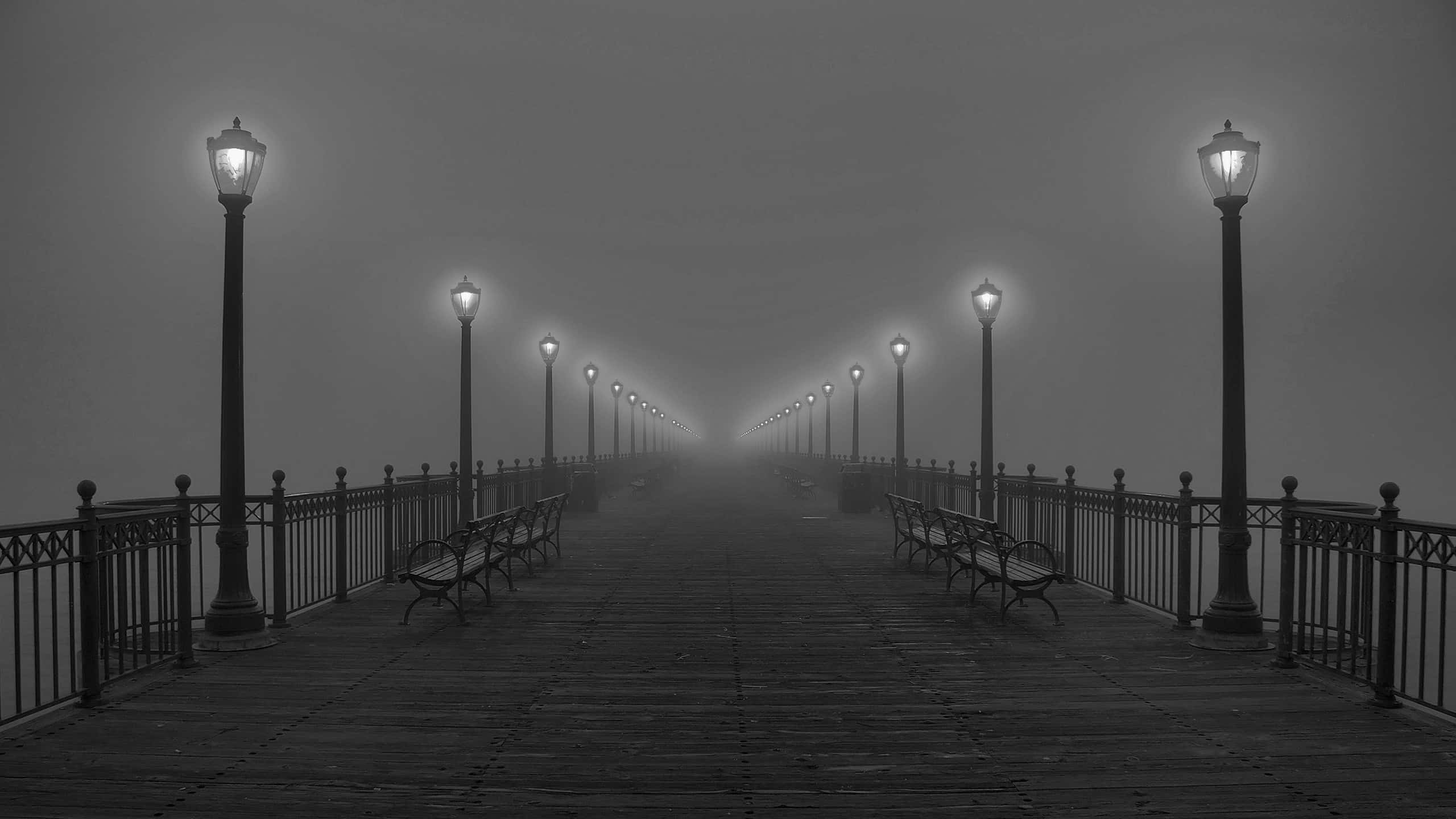 Aesthetic Black And White 桌布 壁紙 — 一條霧濛濛的黑白碼頭延伸進霧中，兩旁有發光的燈籠和空長椅。