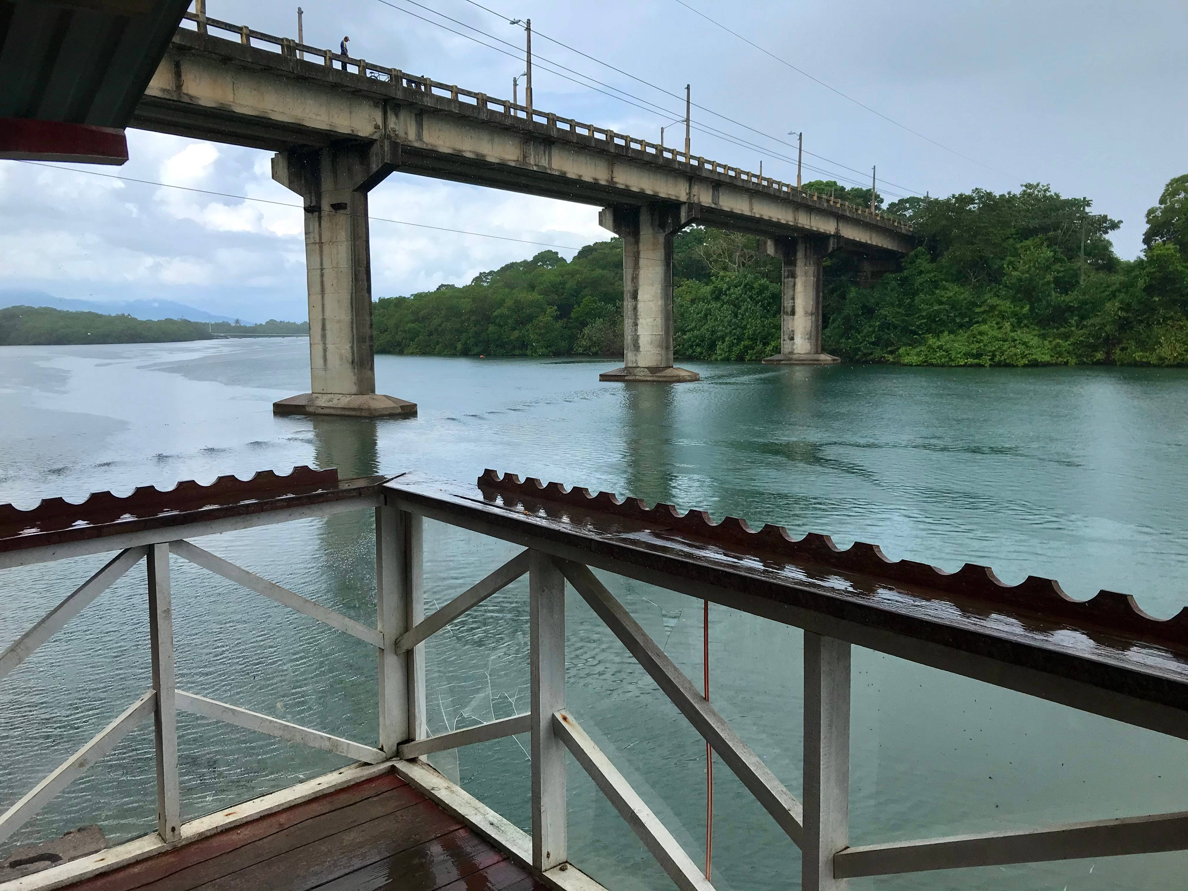 Honduras 桌布 壁紙 — 一條風化的混凝土橋樑橫跨平靜的河流，周圍是茂密的綠色森林，天空多雲。
