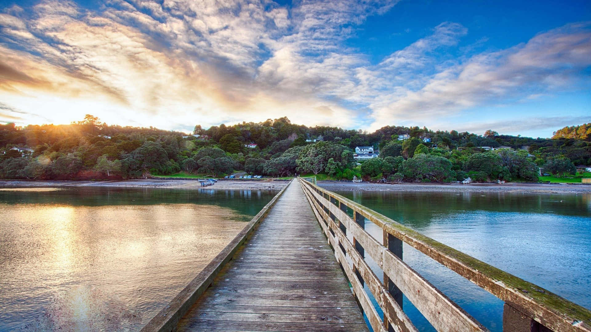 Photography Nature 桌布 壁紙 — 一條飽經風霜的木碼頭延伸至平靜的水面，上方是佈滿散雲的 vibrant 日落天空。