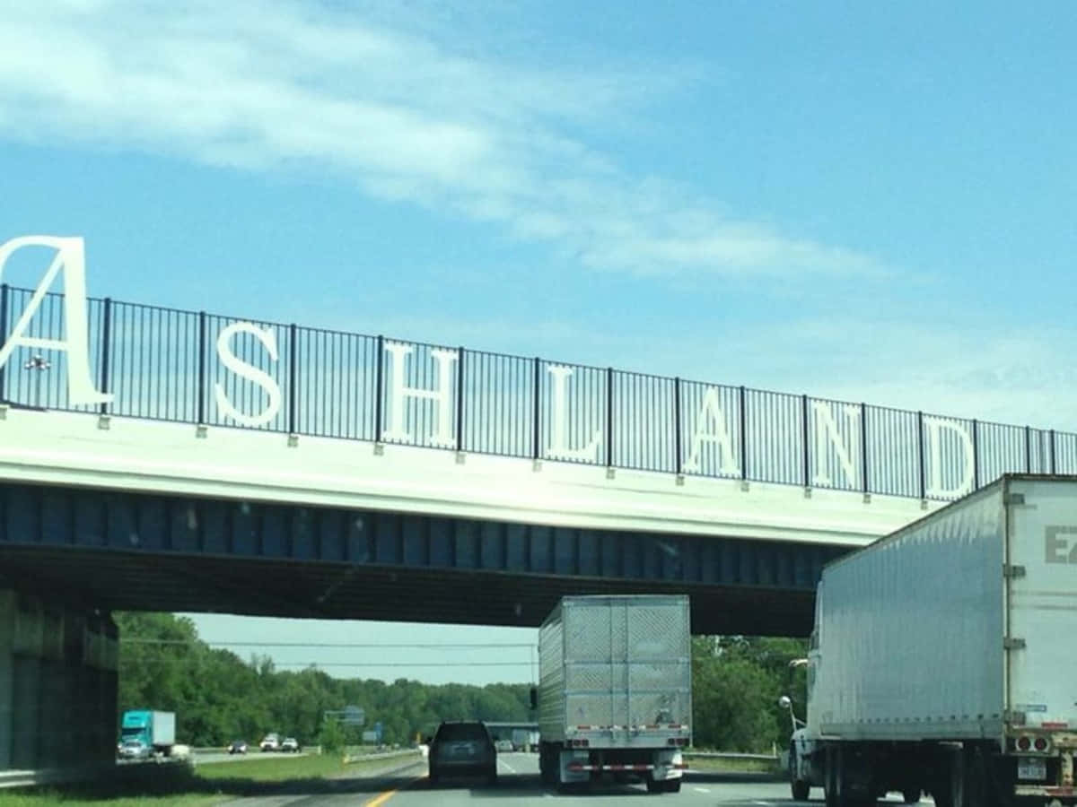 Ashland County 桌布 壁紙 — 一條高速公路位於橋下，橋上有大型白色字母拼寫ASHLAND，背景是清澈的藍天。