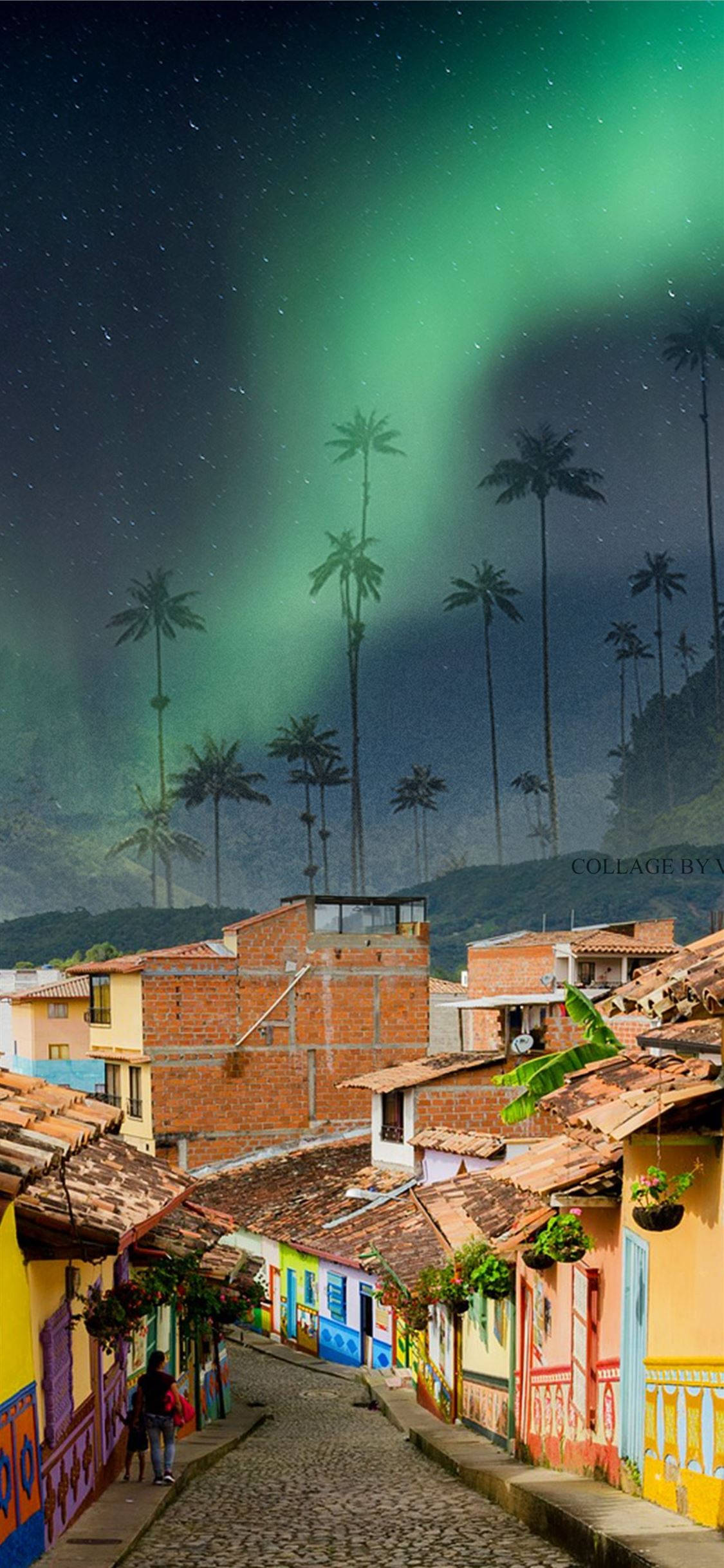 Colombia 桌布 壁紙 — 一條鵝卵石街道，兩旁是色彩繽紛的房屋，星空下閃爍著生動的綠色極光和高大的棕櫚樹。
