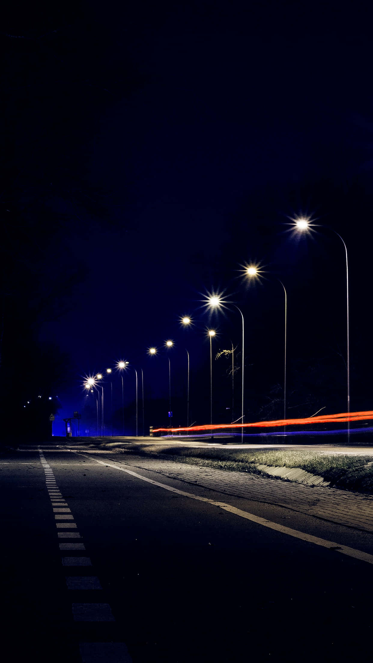 Street Light 桌布 壁紙 — 一條黑暗道路的長時間曝光夜景照片，兩旁有發光的街燈和紅色與橙色車燈的條紋。