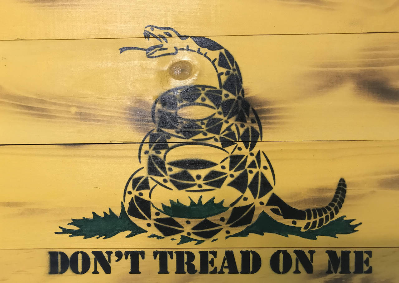 Flag 桌布 壁紙 — 一條黑色幾何圖案的響尾蛇，頭部抬起，露出毒牙，畫在黃色木板上，下方有綠色草地和文字。