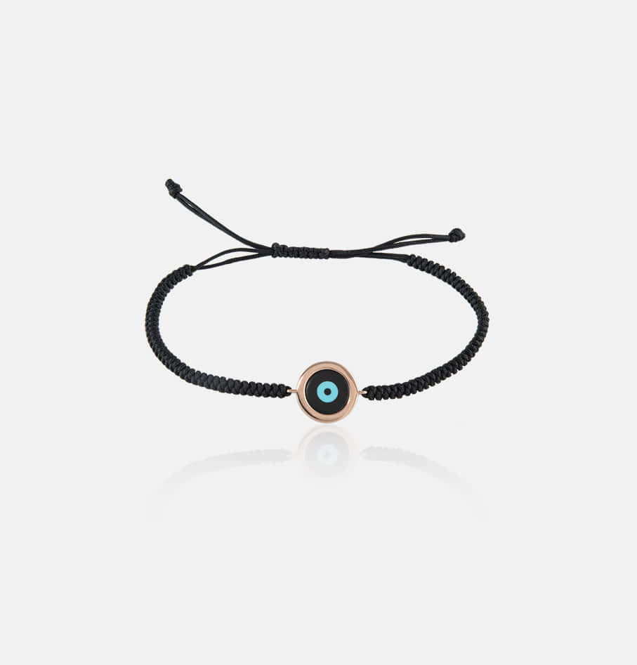 Evil Eye 桌布 壁紙 — 一條黑色編織手繩，帶有玫瑰金邪眼吊飾，放置在反光的白色表面上。