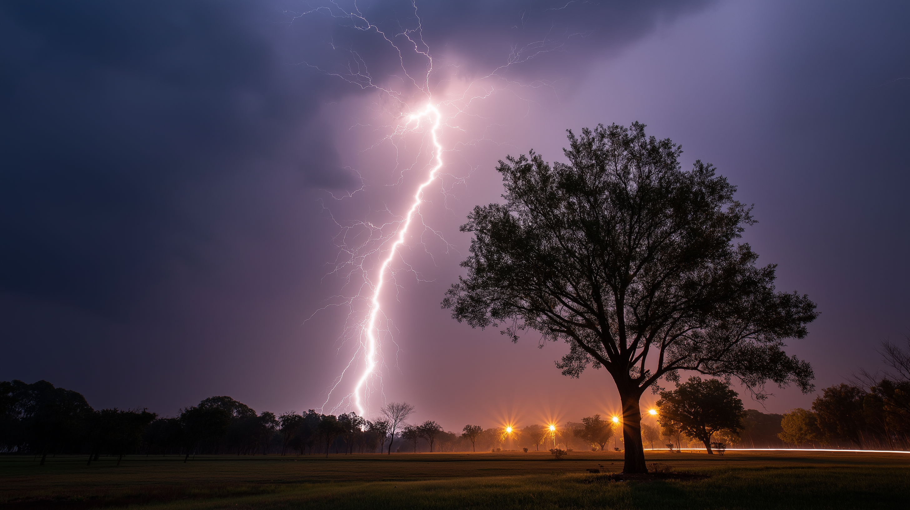 Thunderstorm 桌布 壁紙 — 一棵孤樹在田野中呈現剪影，一道巨大的閃電照亮了暴風雨的紫色天空。