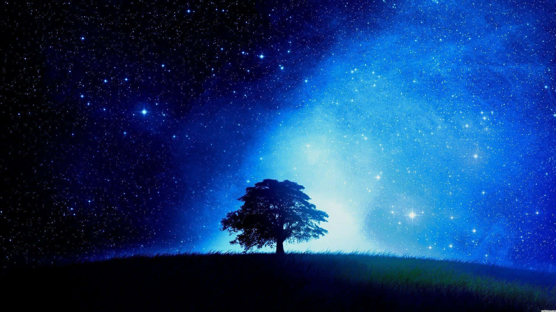 Aesthetic Night Sky 桌布 壁紙 — 一棵孤獨的樹影矗立在長滿草的山丘上，下方是充滿活力的星空，散發著宇宙藍光。