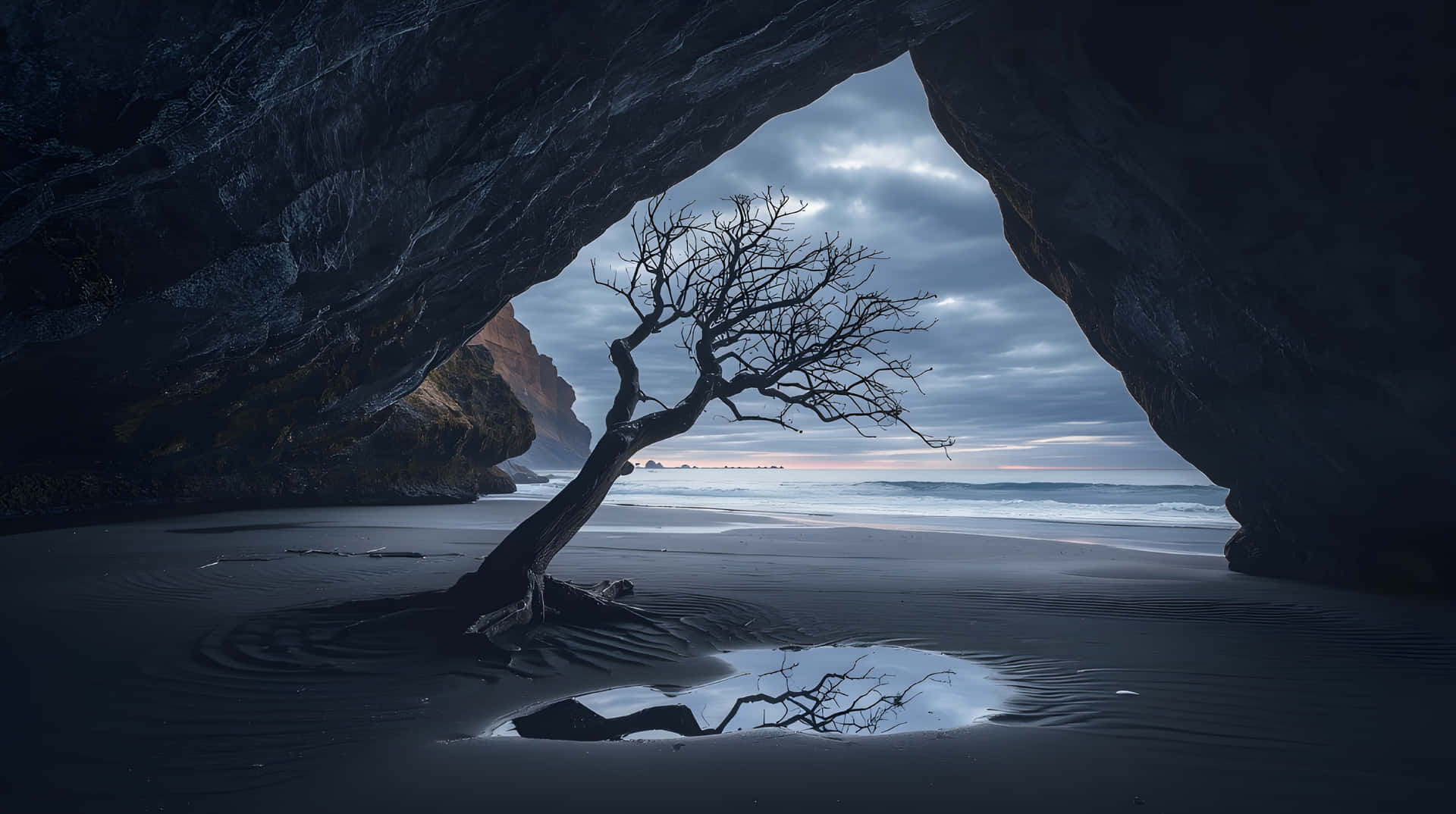 Dramatic Secluded Shore View from Dark Ocean Cave Wallpaper 壁紙 — 一棵孤獨的裸樹矗立在黑沙上，下方是岩石拱門，俯瞰著黃昏時霧氣瀰漫的海洋。
