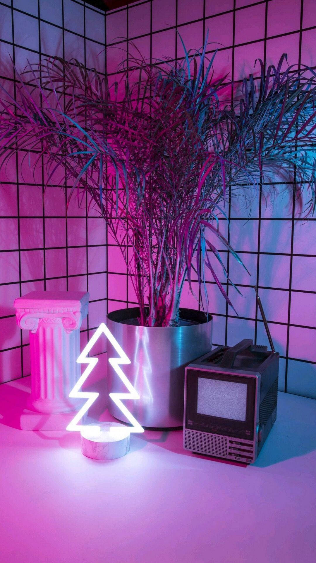 Aesthetic Retro 桌布 壁紙 — 一棵復古霓虹樹在復古電視和盆栽植物旁邊發出粉紅色光芒，網格牆沐浴在充滿氛圍的粉紅色和藍色燈光中。