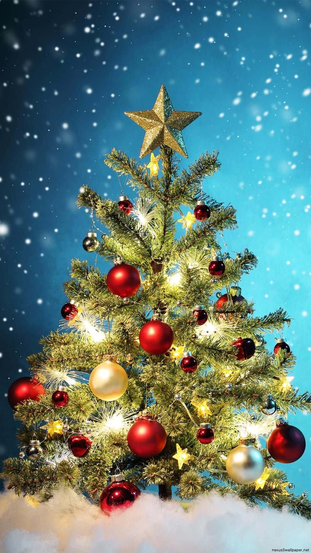 Christmas Cell Phone 桌布 壁紙 — 一棵明亮的聖誕樹，裝飾著紅色、金色和銀色的飾品，頂端有一顆星星，在飄雪中矗立於藍天下。